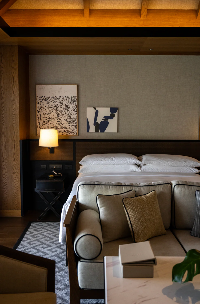 Contemporary hotel room interior with neutral tones and modern artwork above bed.