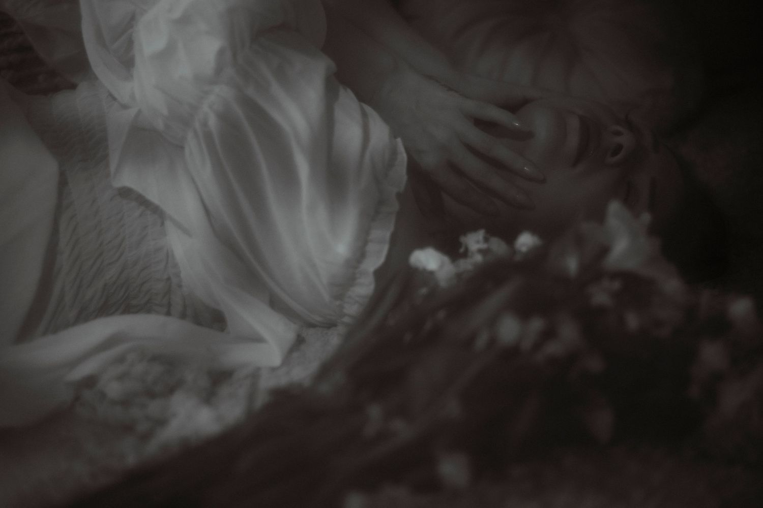 Dreamy black and white close-up of white fabric and delicate small flowers.