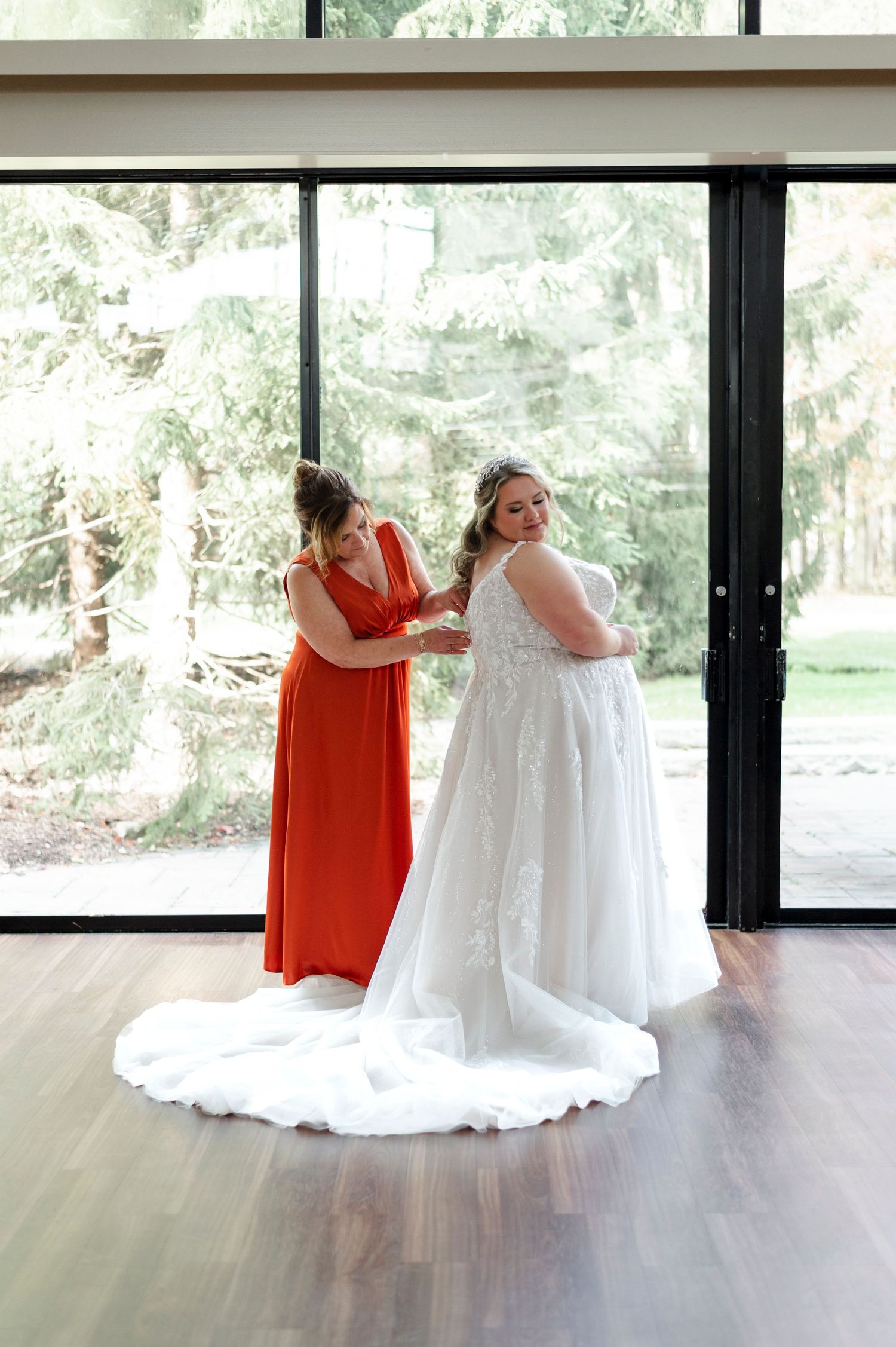 Two people in formal attire share a tender moment during a wedding, one in red and one in white.