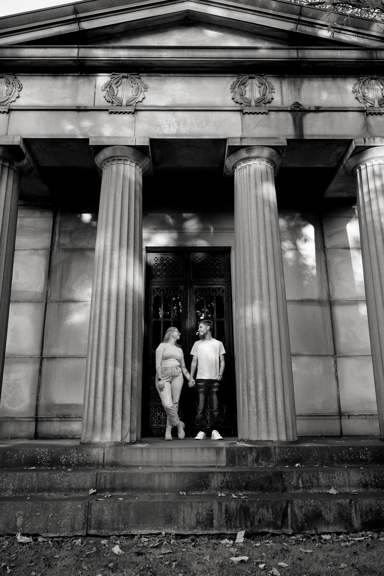 Black and white architectural photograph showing figures silhouetted against classical columns of a building entrance.