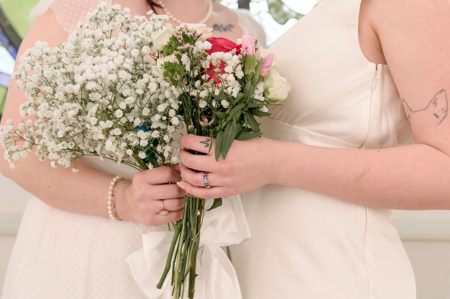 Wedding party members holding delicate white floral bouquets against light-colored dresses.