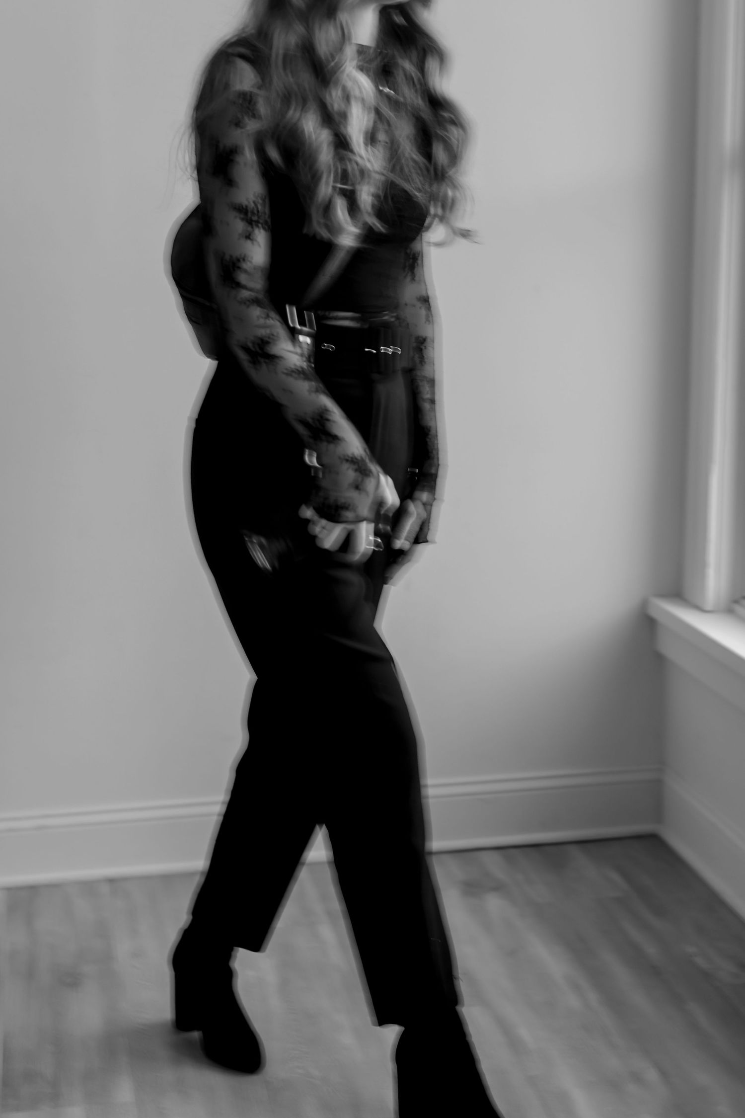 A series of black and white photos showing a person in dark clothing dancing and moving expressively against a light wall.