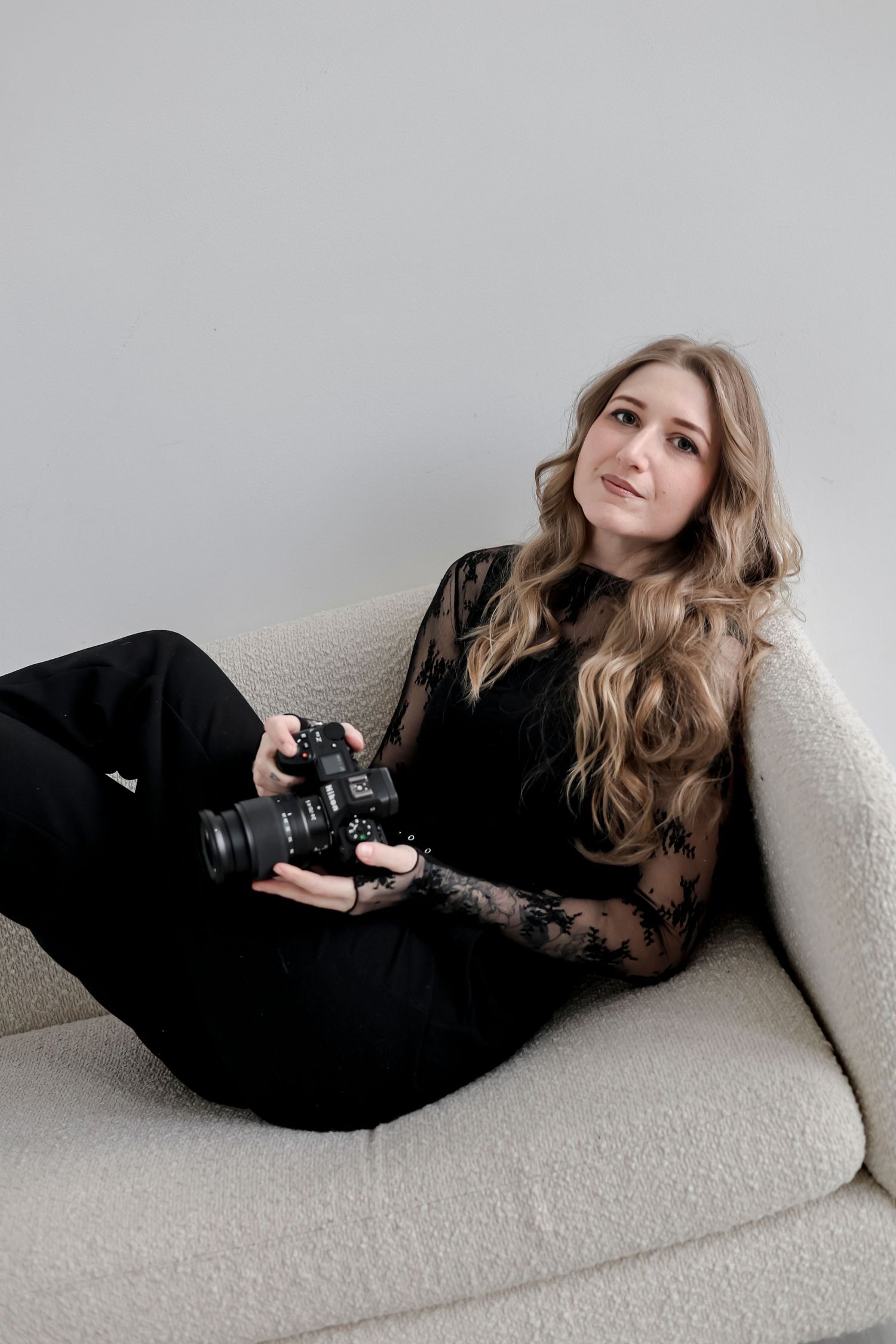 A series of fashion portraits showing a model in a black dress reclining on a white couch in different poses.