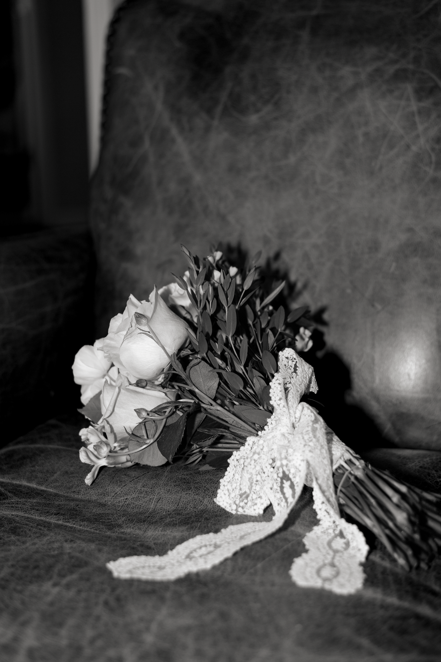 Black and white photo of a delicate bridal bouquet lying on a textured surface.