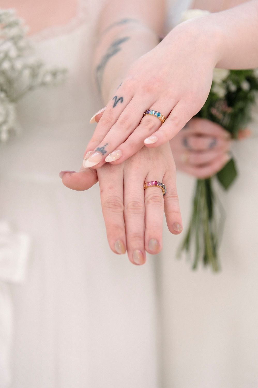 Close-up of hands showing wedding rings and elegant manicures.