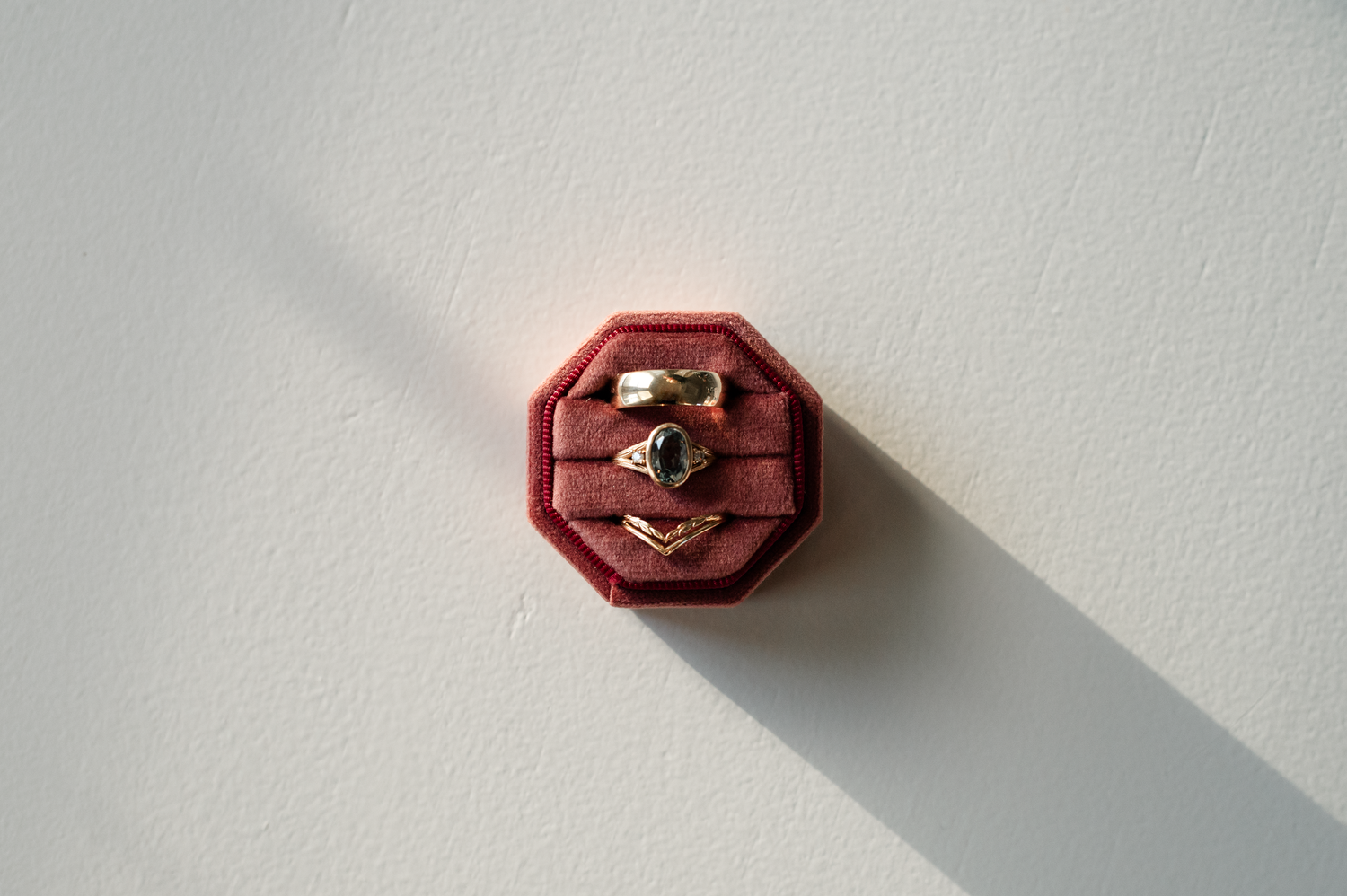 Minimalist photos of a burgundy octagonal ring box on white background.