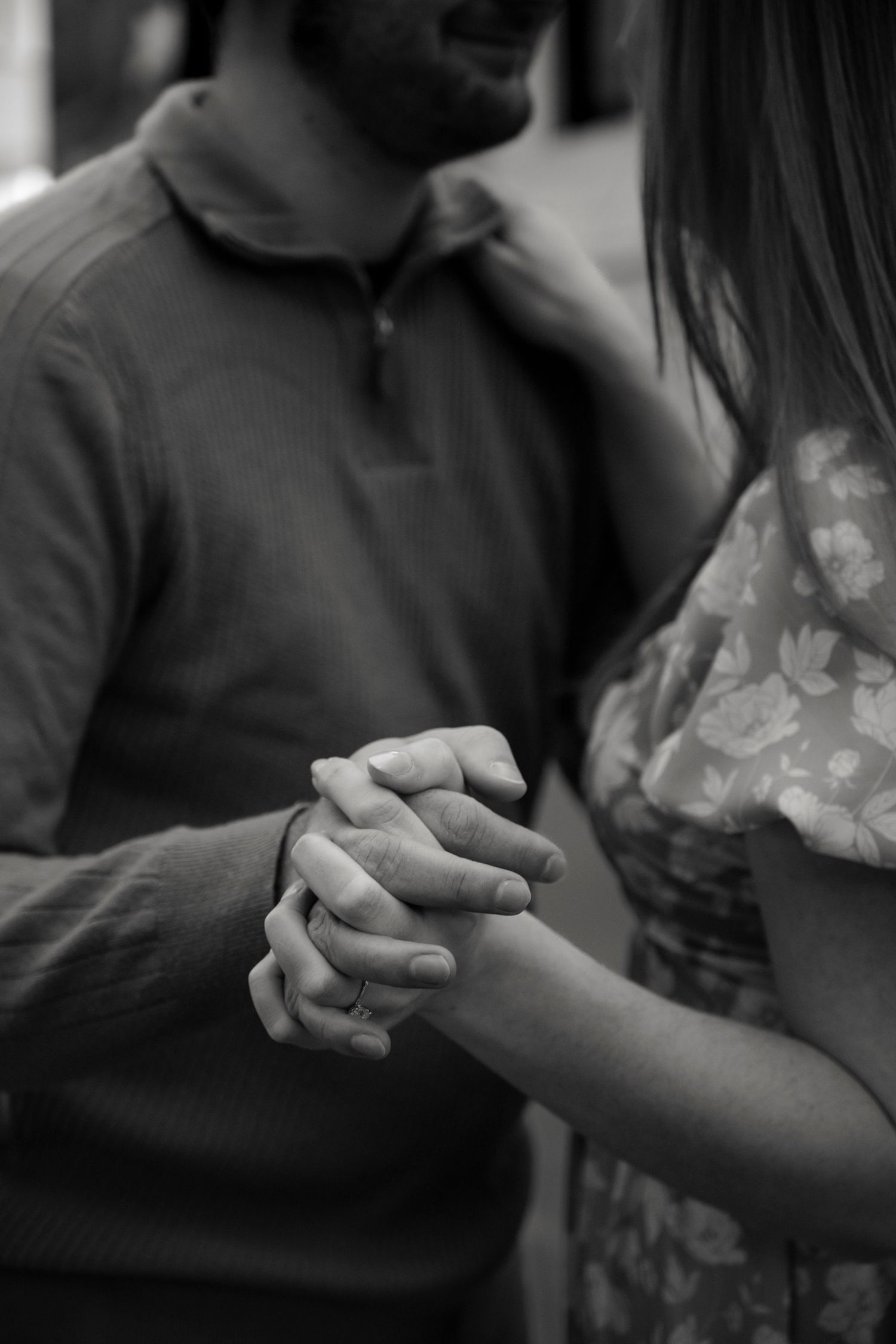 A black and white close-up photo of two people holding hands intimately.