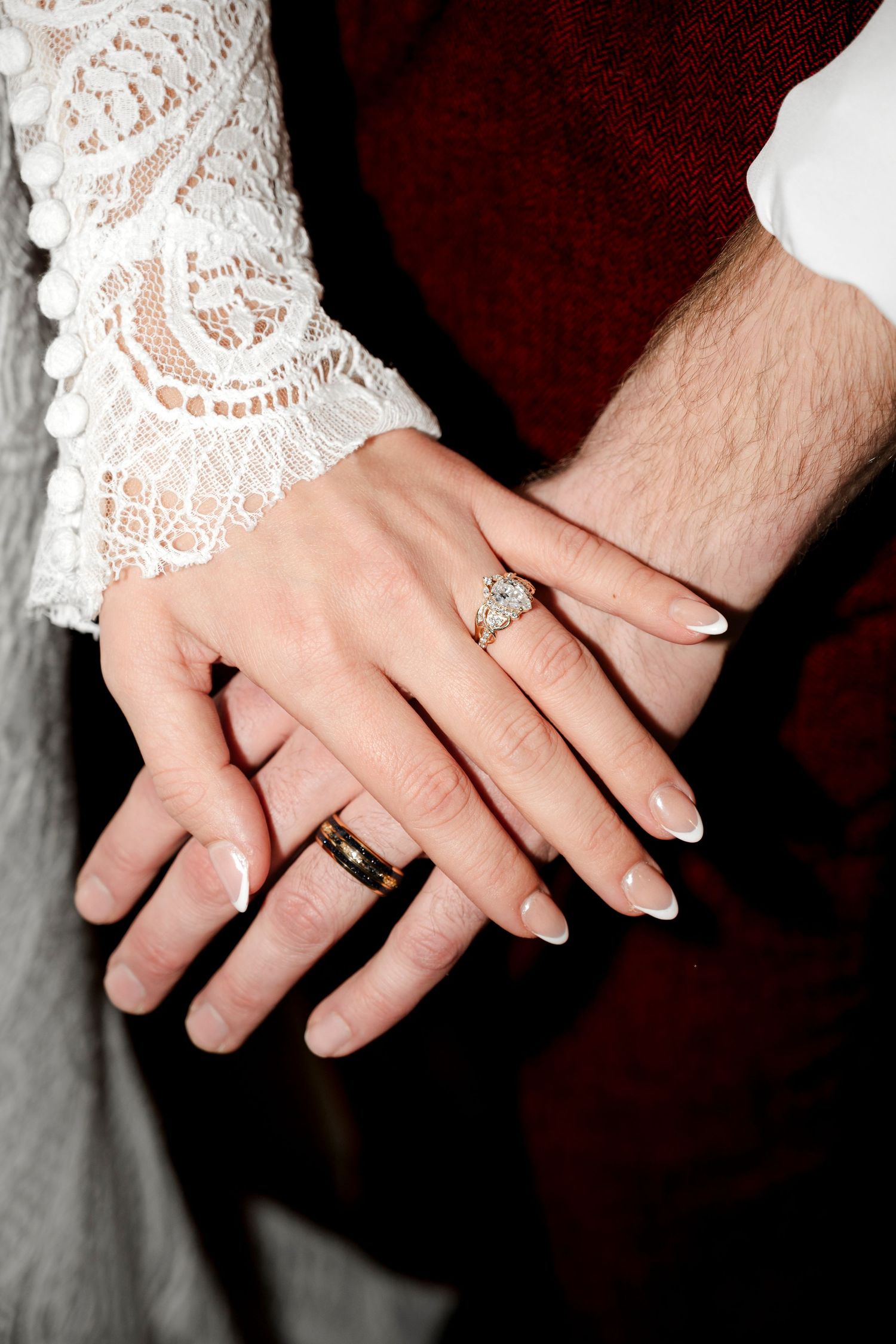 Hands of a couple wearing wedding rings, with the woman's hand adorned with a diamond engagement ring.