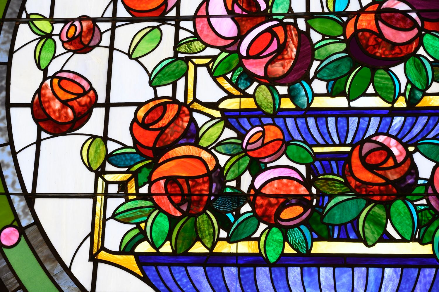Colorful stained glass window panel featuring red roses and green leaves in an Art Nouveau style design.