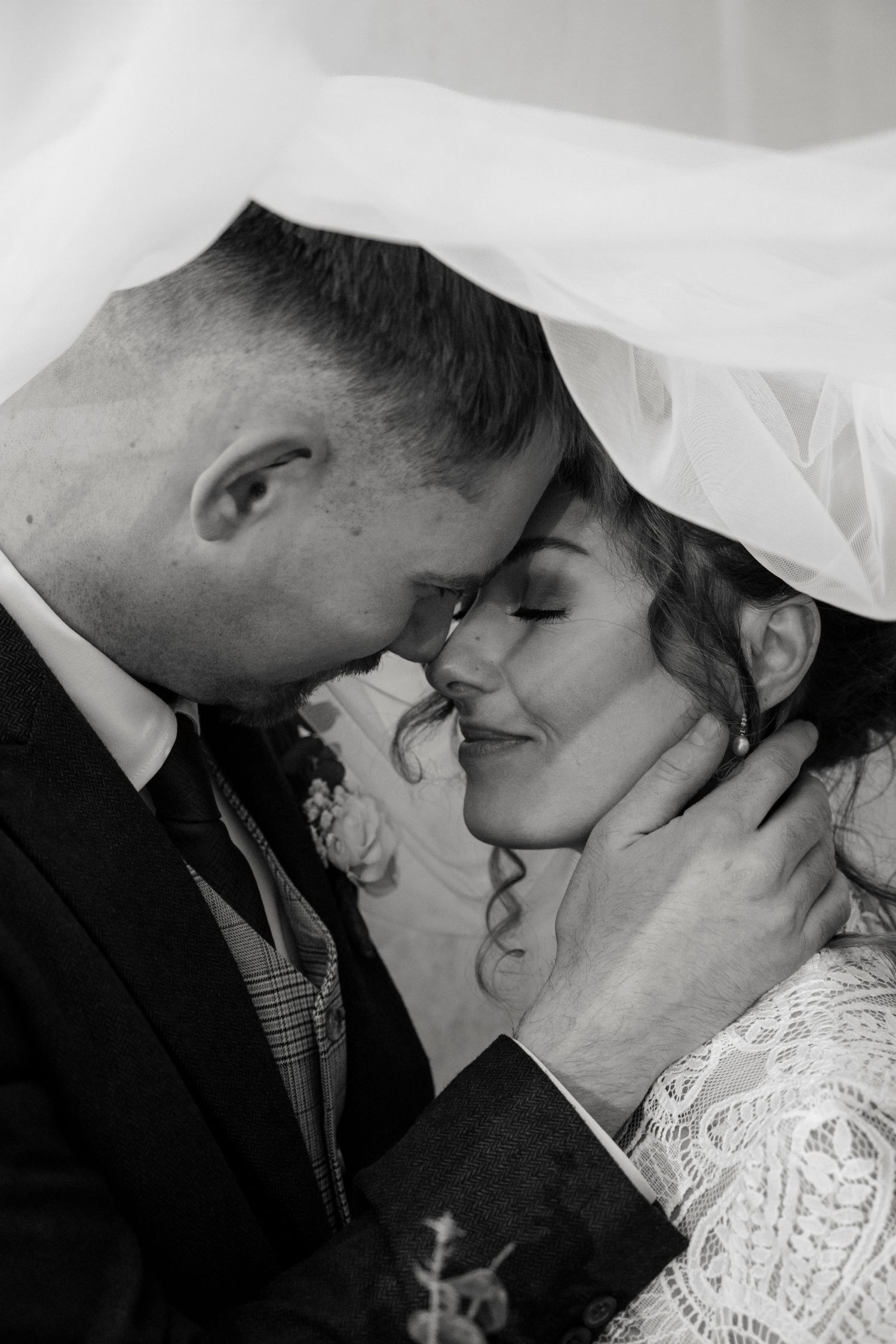 A romantic black and white photo sequence showing a couple sharing tender kisses under a veil during their wedding.