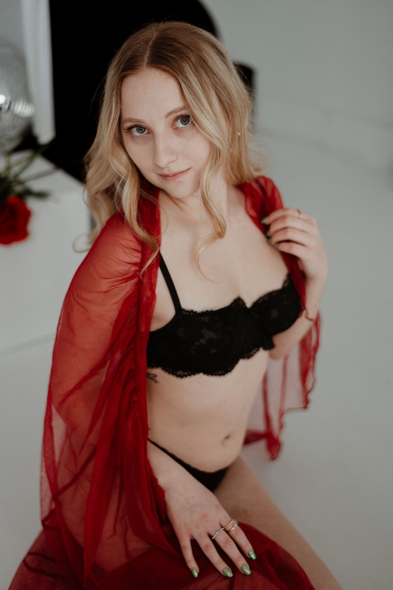 Boudoir photo series featuring a woman in black lingerie and sheer red robe against a white backdrop.