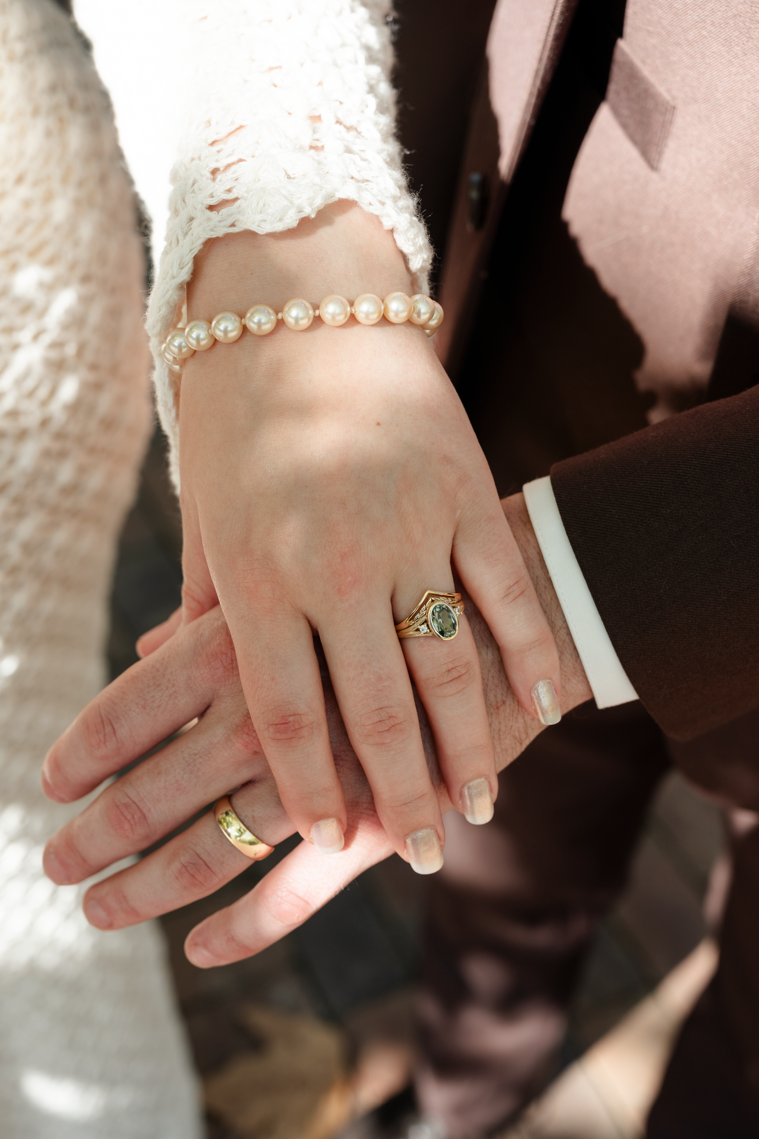 Close-up series of hands showing wedding rings and jewelry against a white lace background.