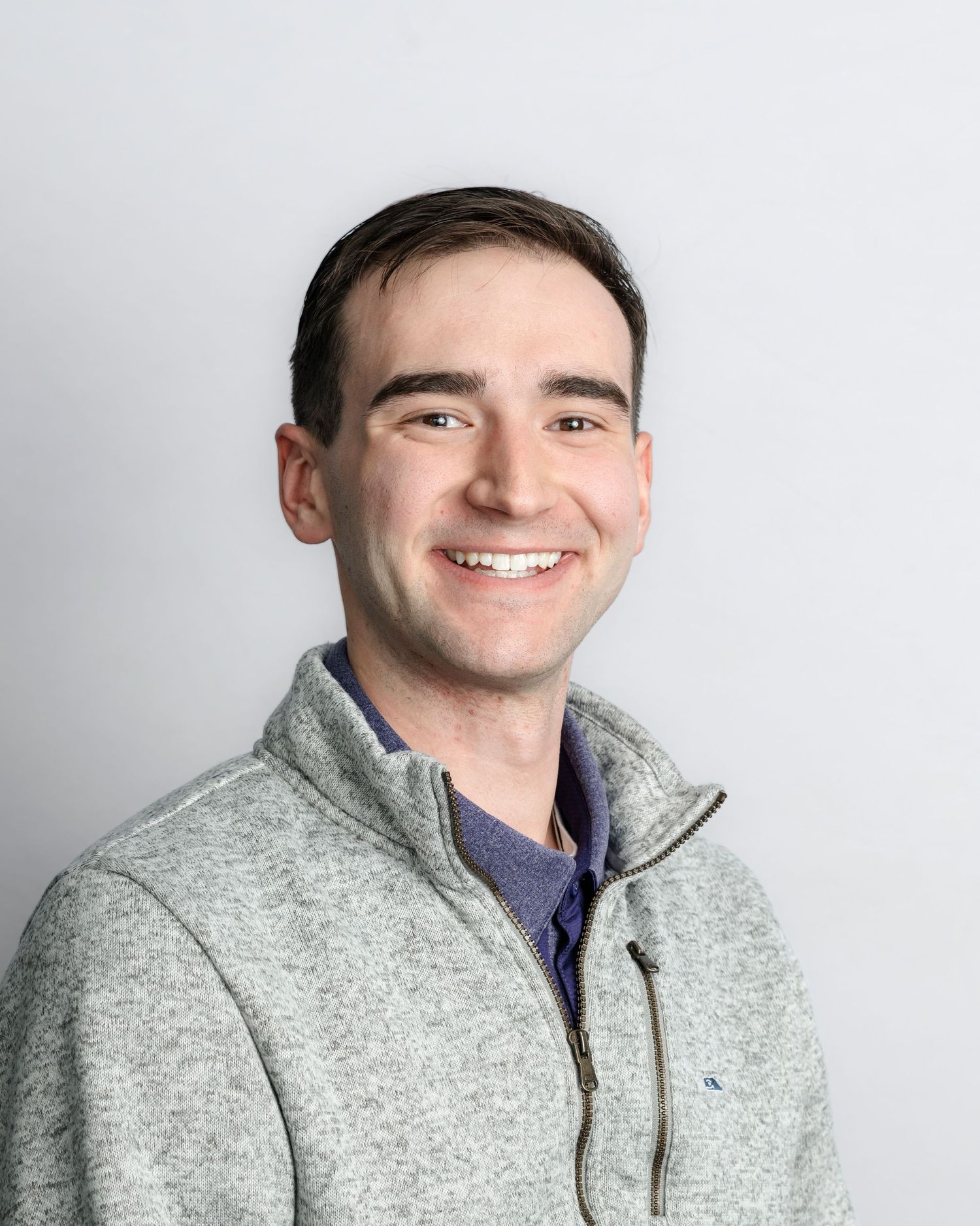 Portrait series featuring someone wearing a light gray zip-up sweater against a white studio backdrop.