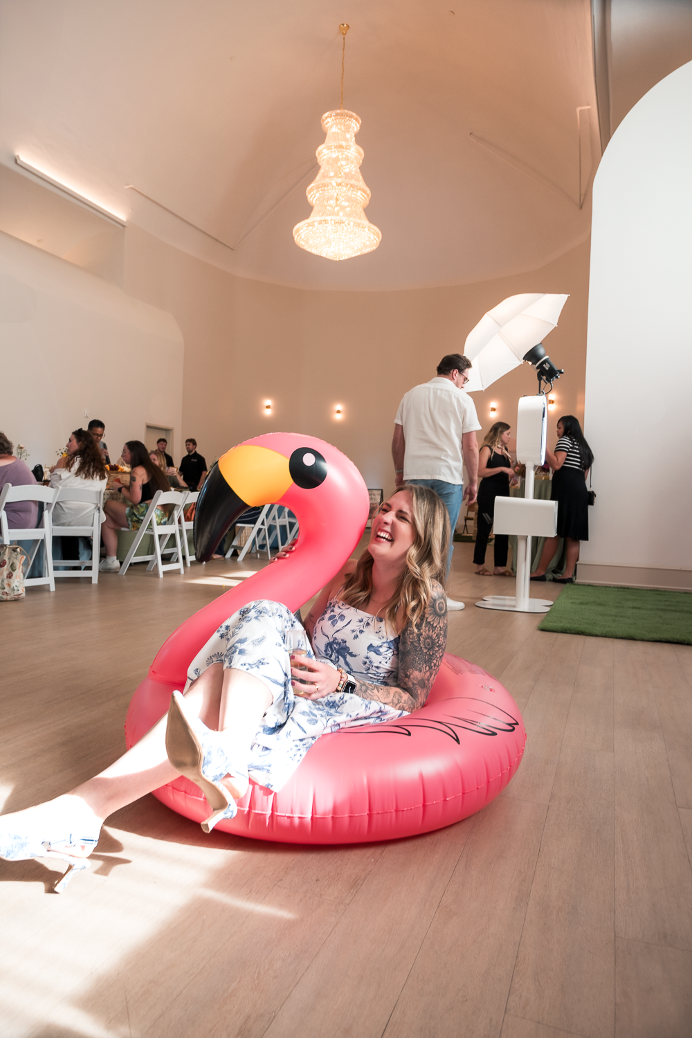 A series of photos showing a large pink flamingo pool float in a bright indoor event space with wooden floors.