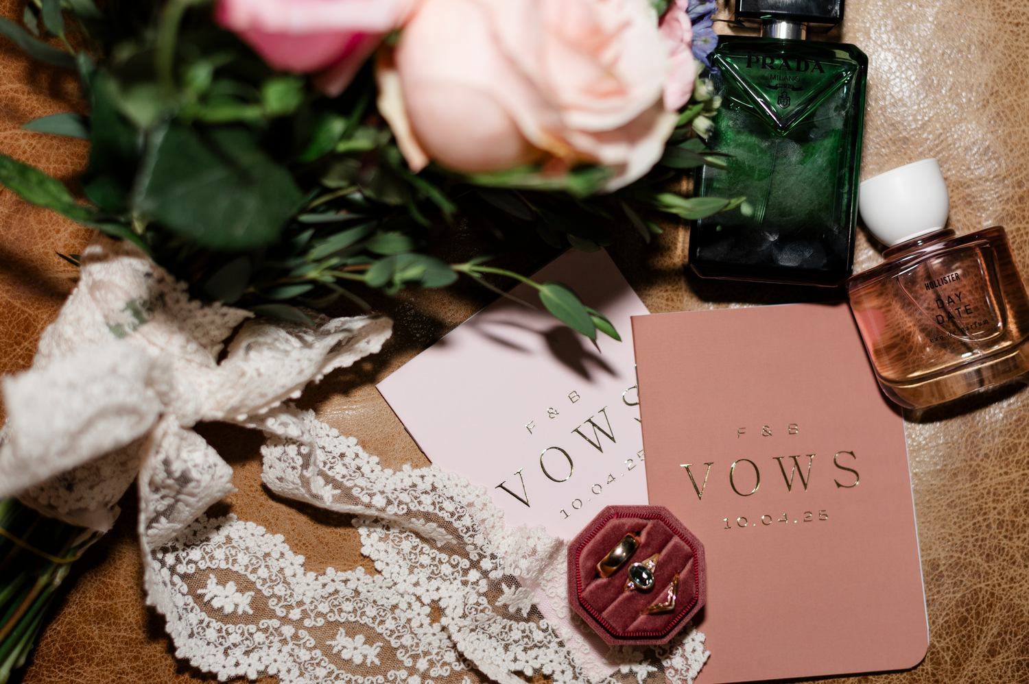 Wedding invitation suite with pink roses, burgundy wax seal, and lace details on rustic wooden background.