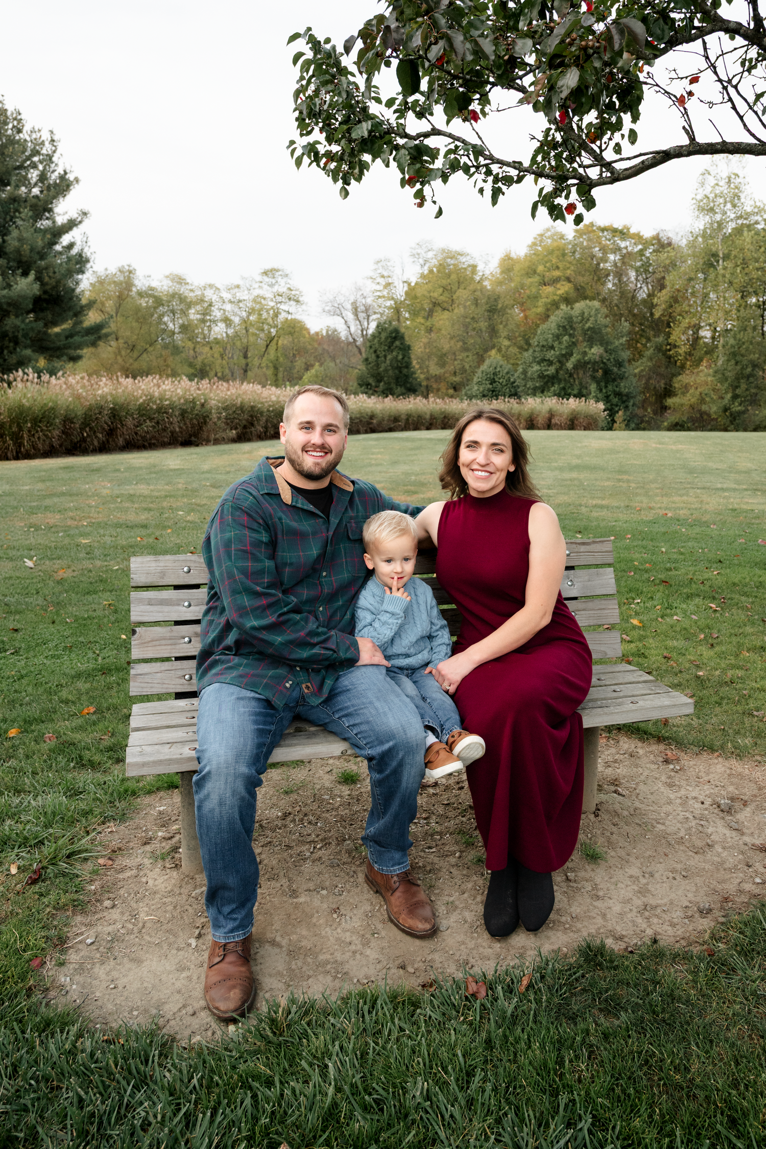 Family sitting together on a wooden bench in a peaceful park setting.