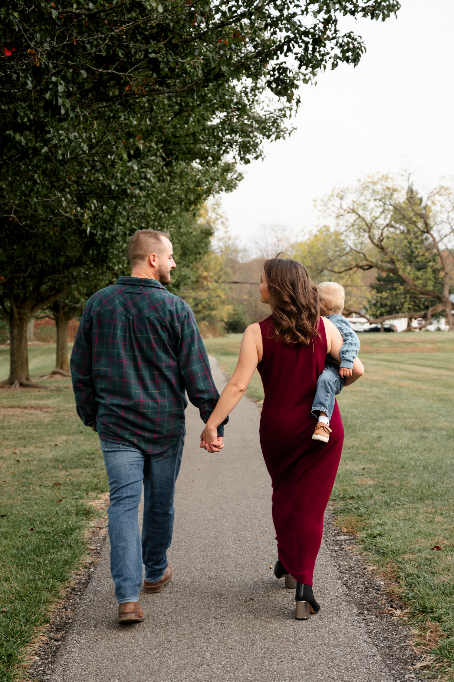 Family walking together on a path through an autumn park landscape.