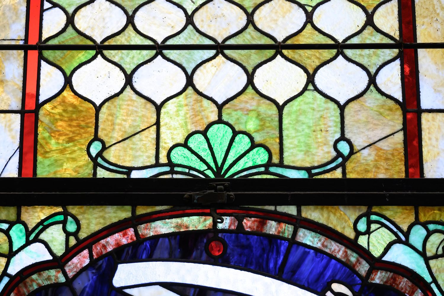 Ornate stained glass window with geometric patterns and floral designs in vibrant colors.