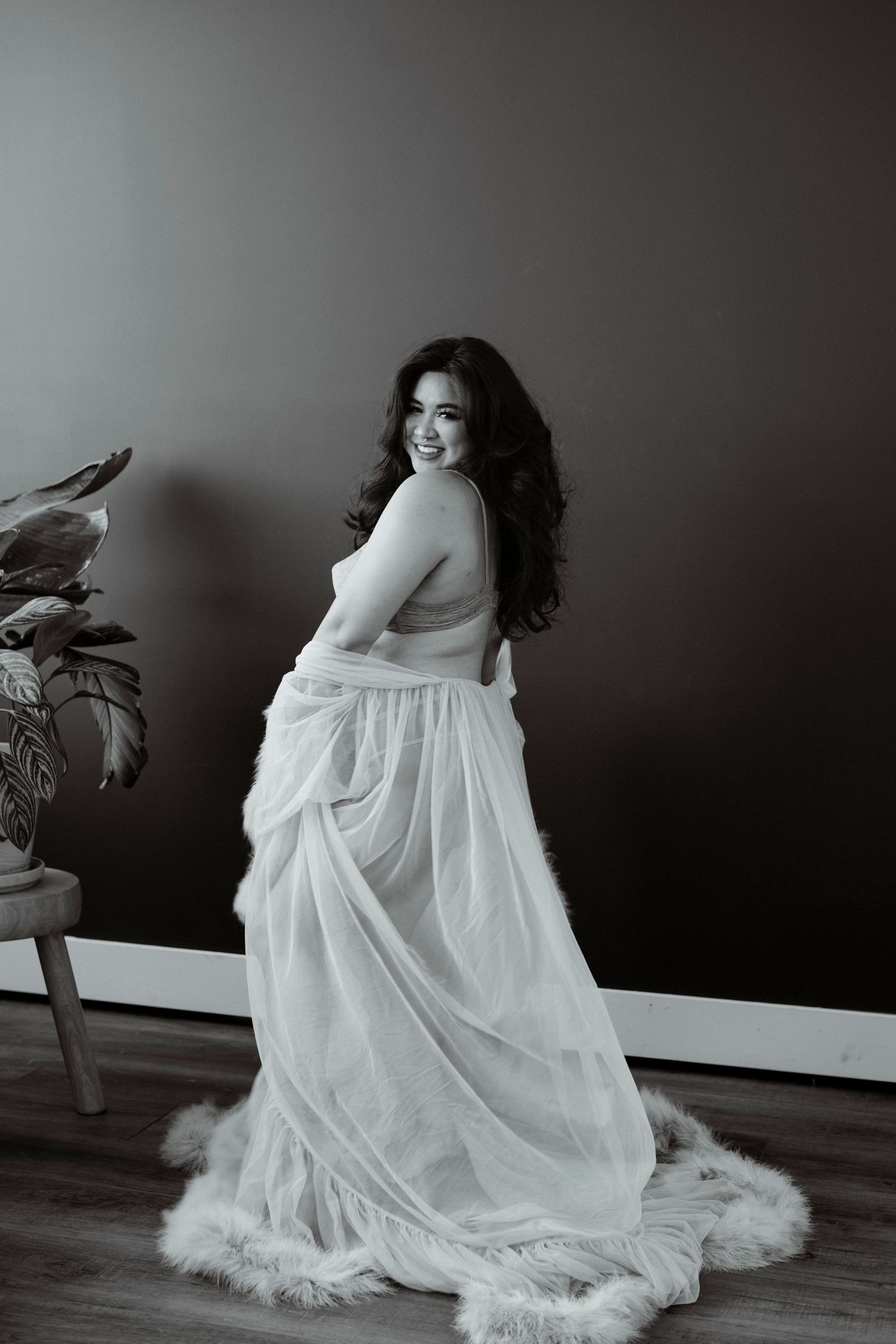 A dramatic black and white photo series shows a flowing white dress with feather trim against a dark background.