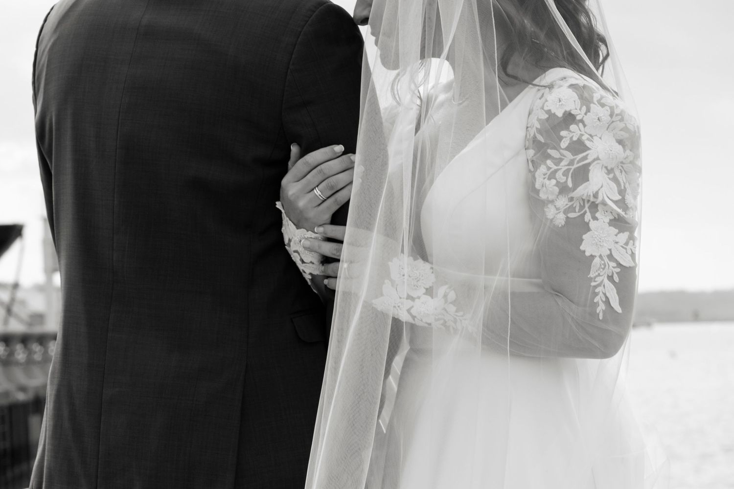 A bride and groom share a tender moment during their wedding ceremony, captured in a black and white photograph.