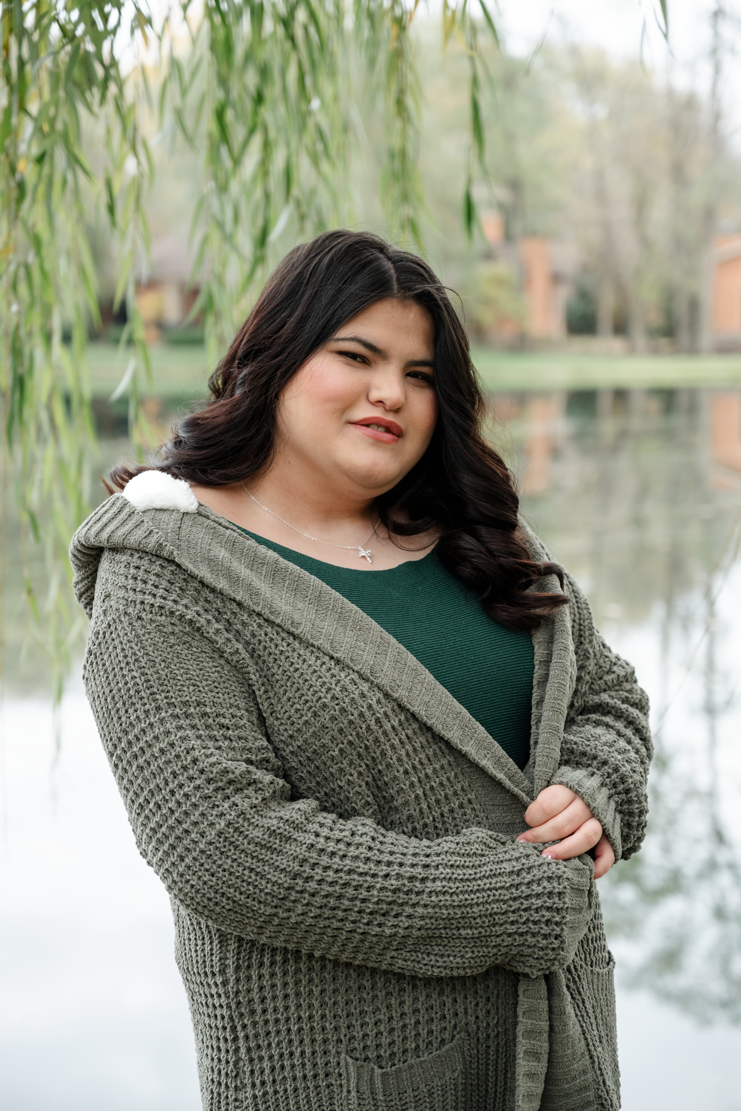 A series of outdoor portraits showing a person in a chunky knit cardigan and green top posing near a willow tree by a lake.