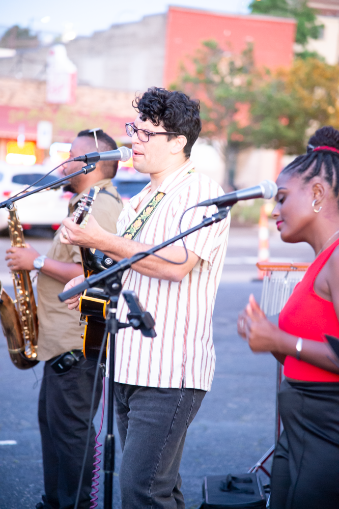 Musicians performing outdoors with saxophones and microphones at a street concert.