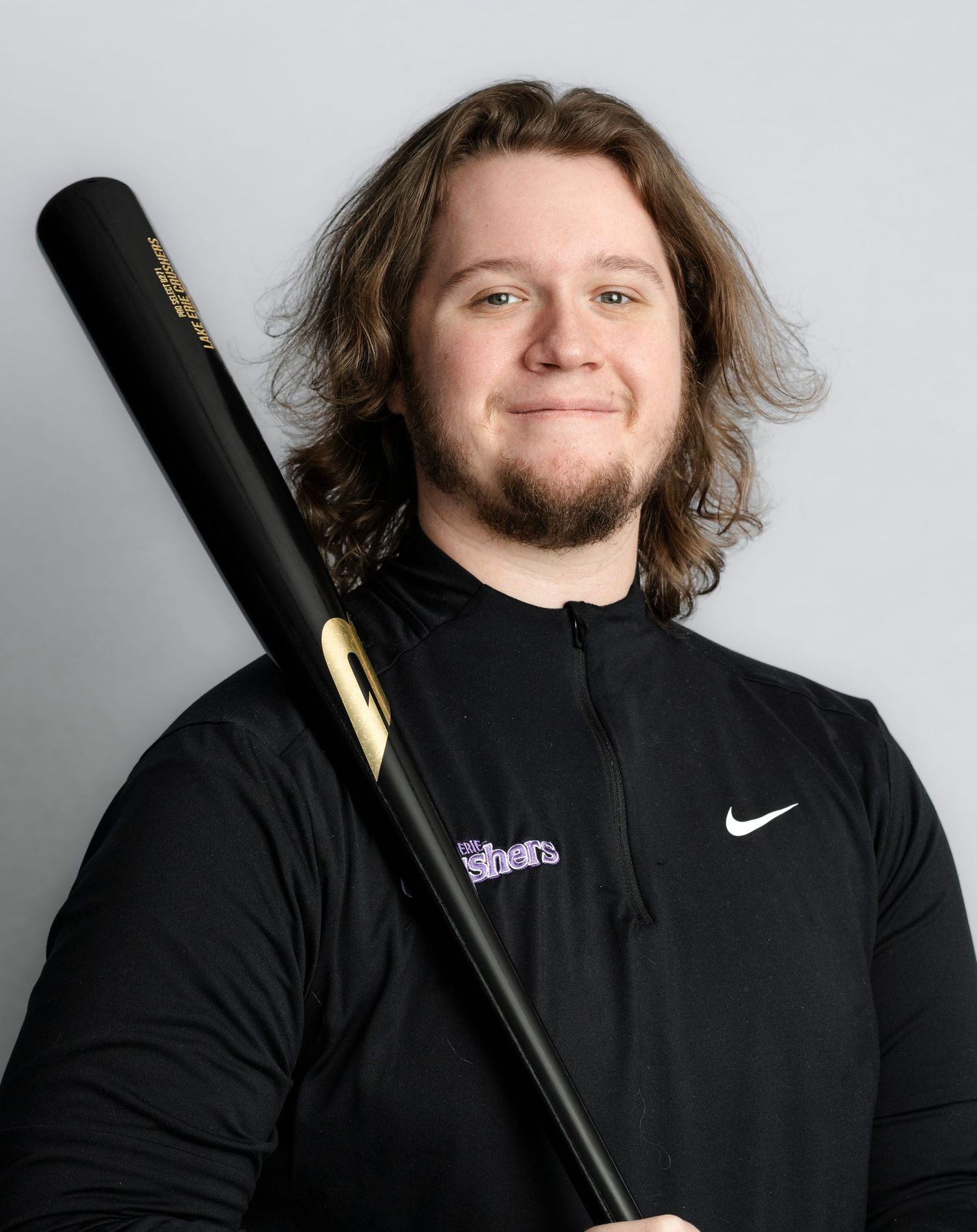 Baseball player wearing a black Nike jacket holding a bat in studio portraits.