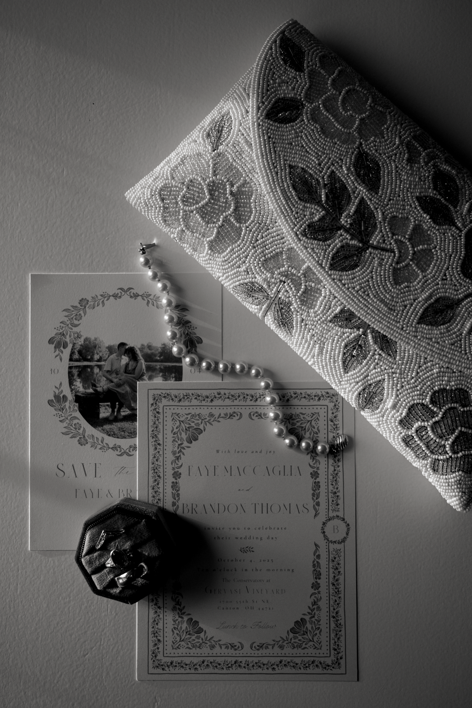 Artistic black and white photo of wedding invitations with pearls and lace details.
