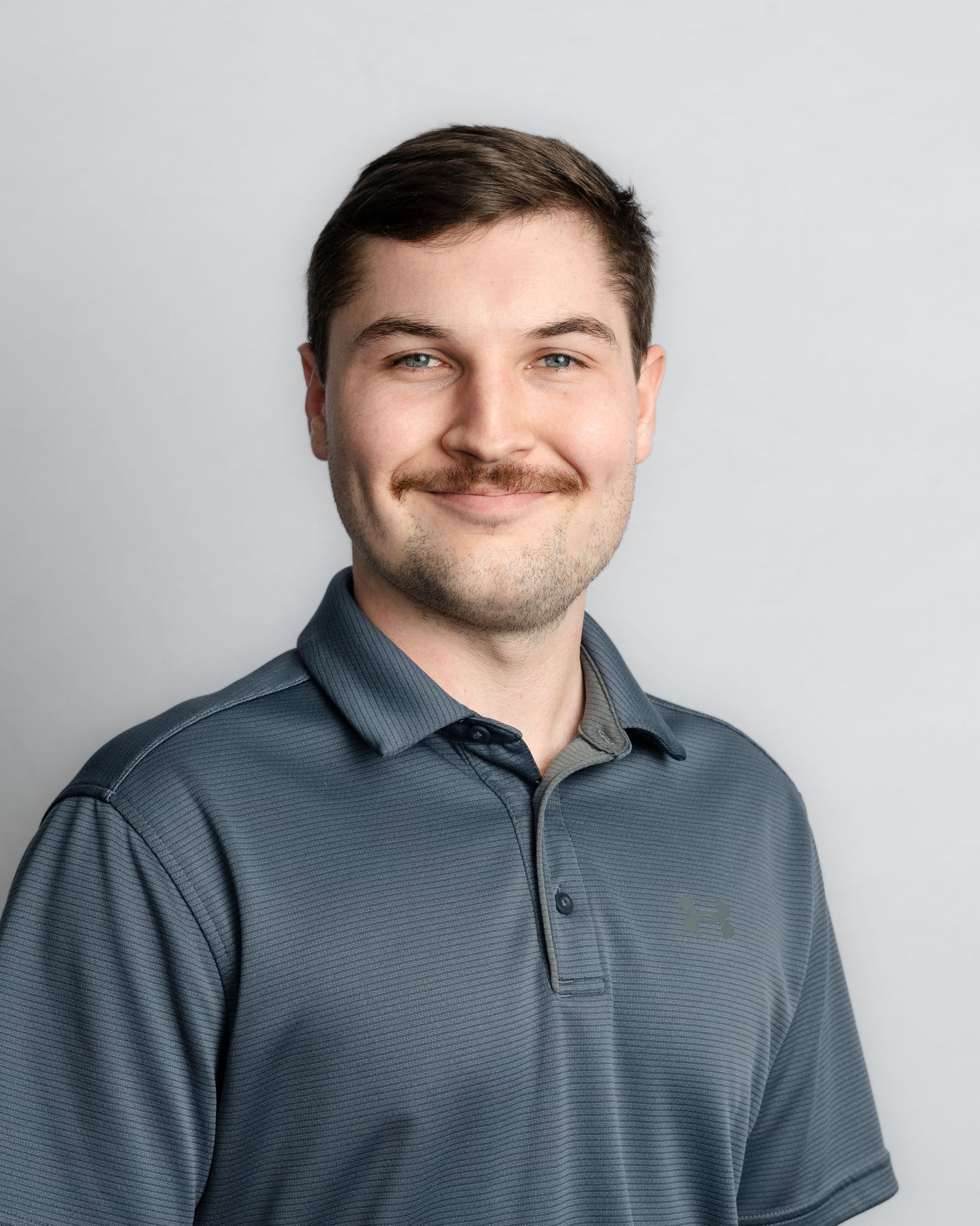 Professional headshot sequence showing different expressions while wearing a gray polo shirt against white background.