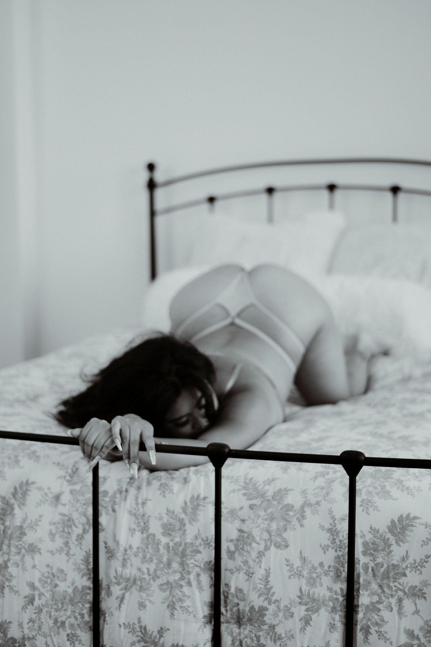 Black and white artistic photograph series showing someone resting peacefully on a bed with decorative metal headboard.