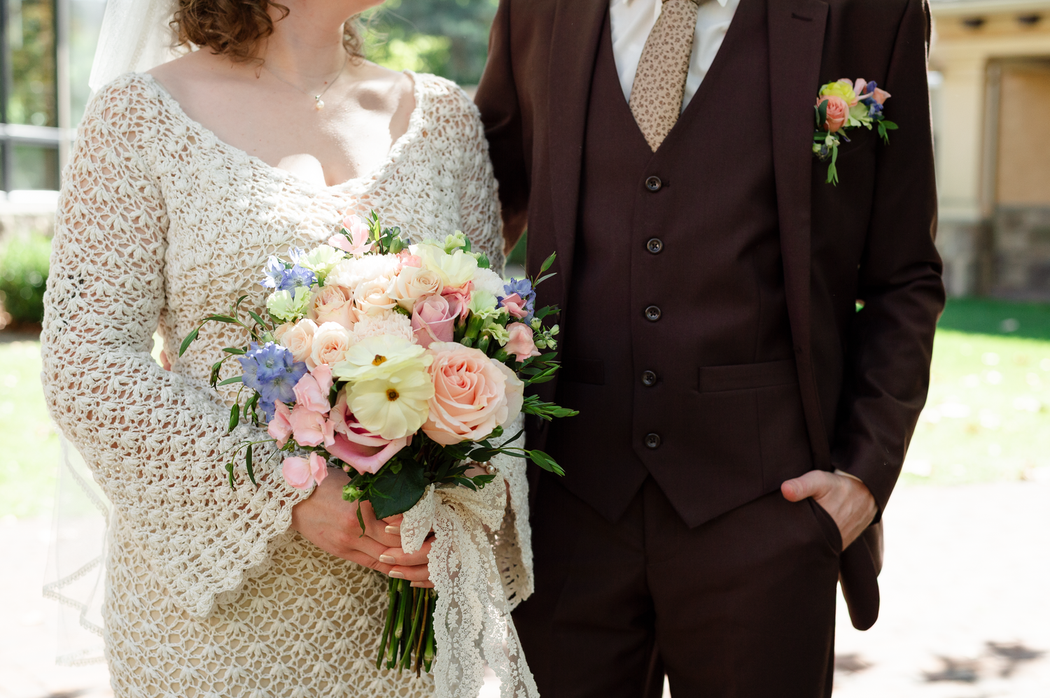 A bridal bouquet featuring soft pink and peach roses with delicate lace details in the background.