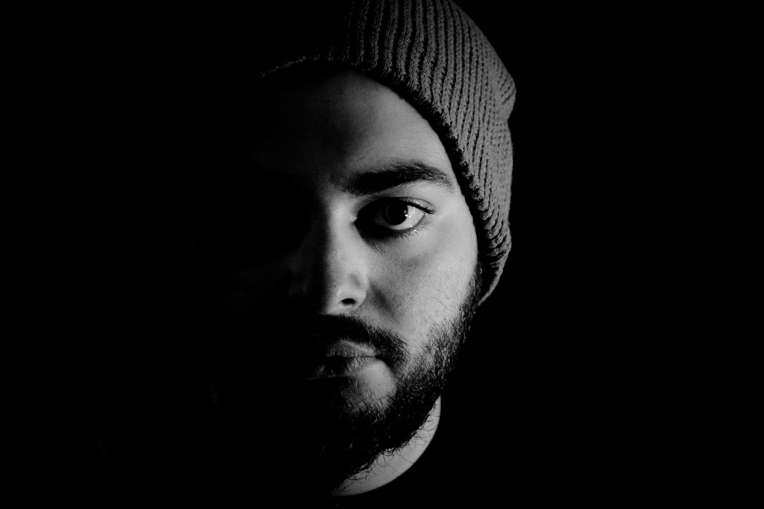 A series of dark black and white close-up portraits showing partial faces in shadow wearing winter hats.