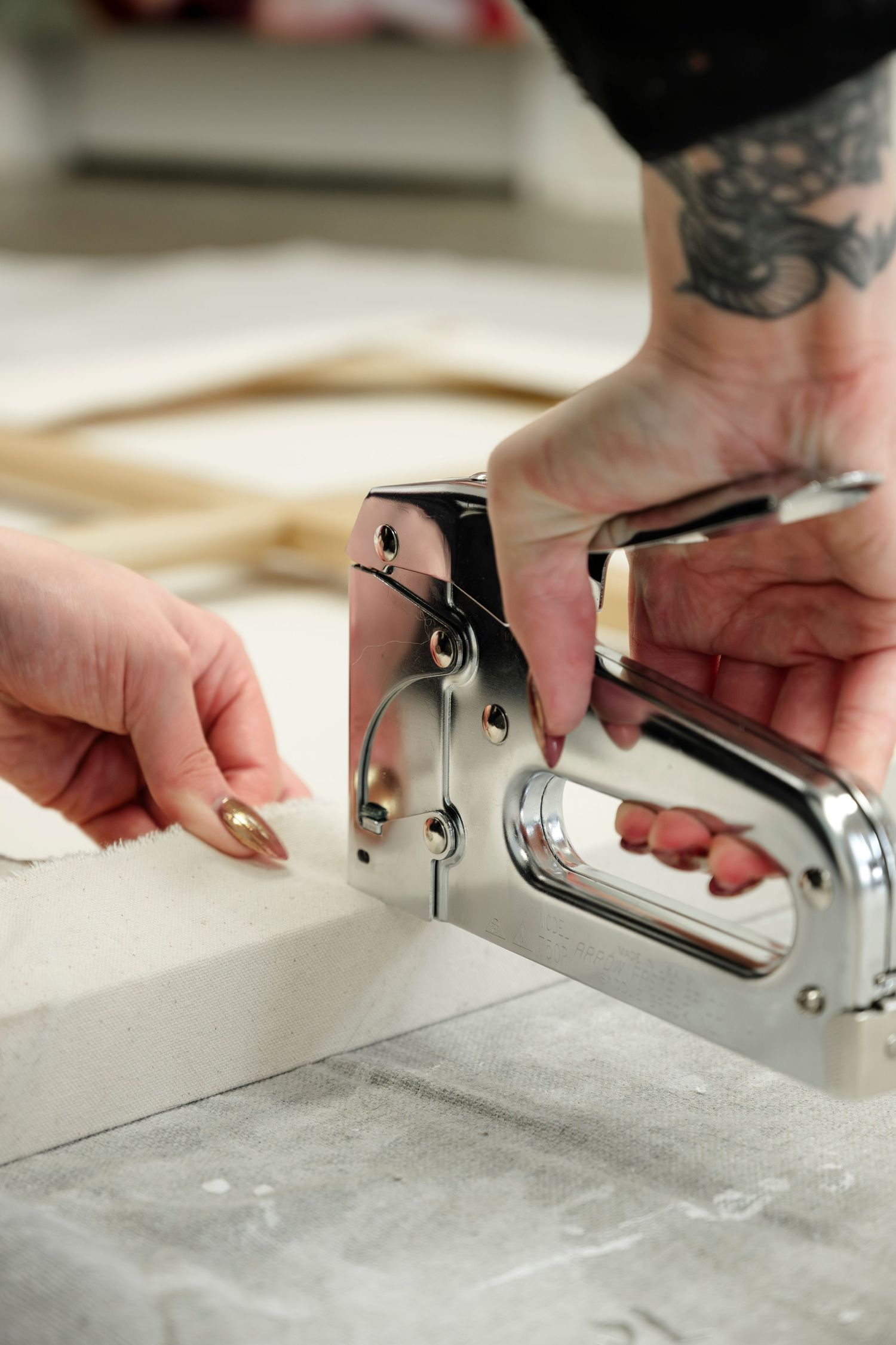 Hands with tattoos using a staple gun on a light colored surface in a series of sequential shots.