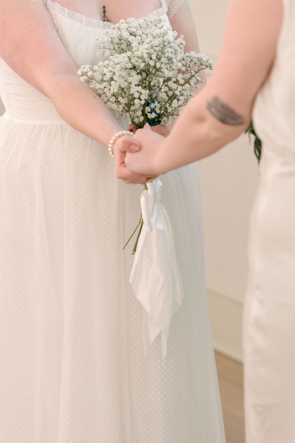 White baby's breath bouquets held against white dresses in a bridal party lineup.