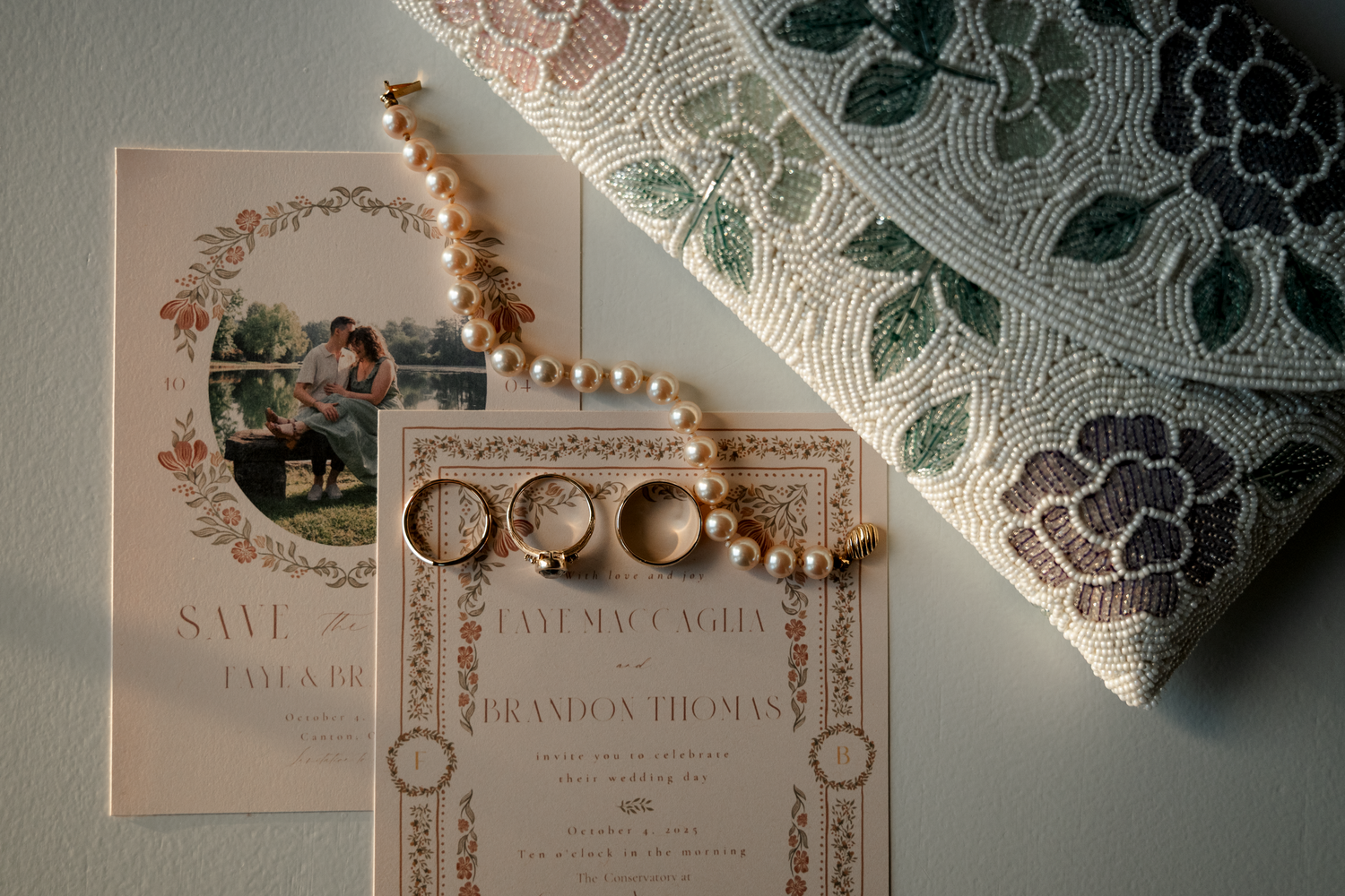 Wedding invitation suite with delicate lace details and gold rings arranged on a light beige surface.