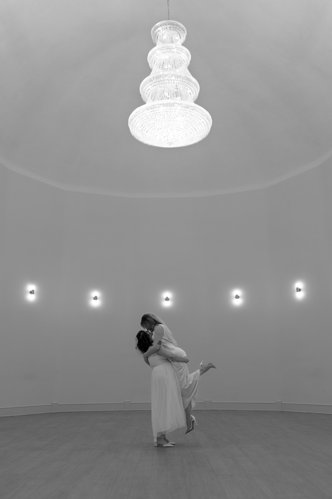 Dancers perform in a minimalist white circular space with evenly spaced wall lights.