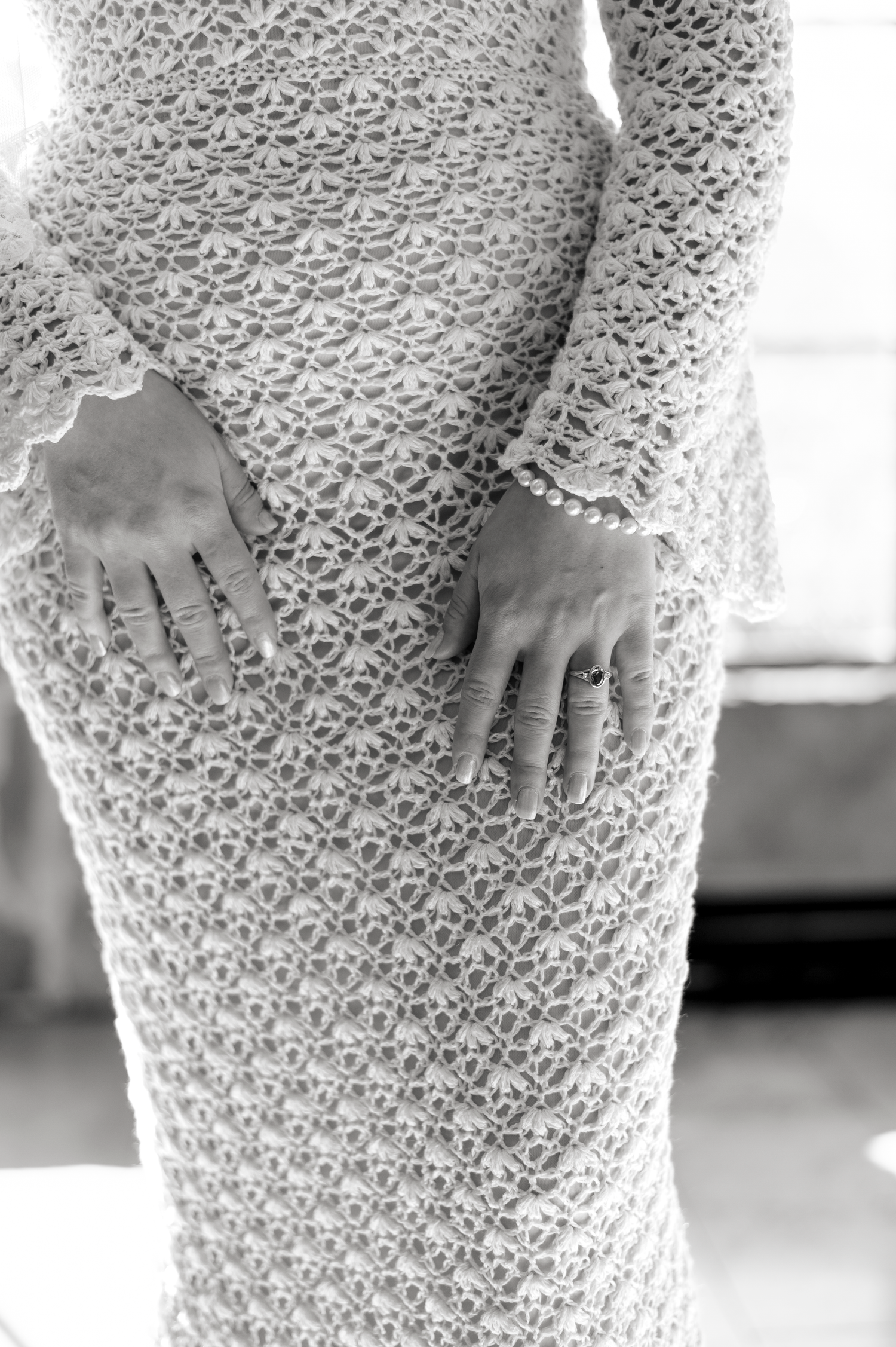 Detail shot of intricate white lace pattern on wedding dress fabric.