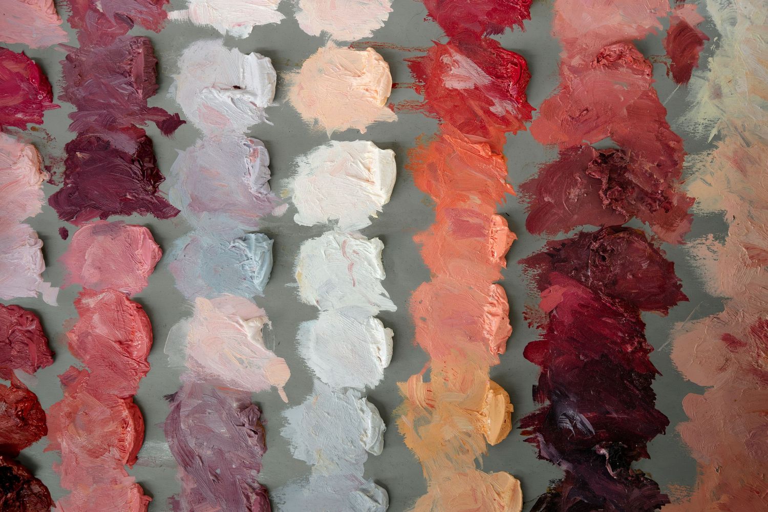 Abstract painting with textured brushstrokes in shades of red, pink, and coral against a gray background.