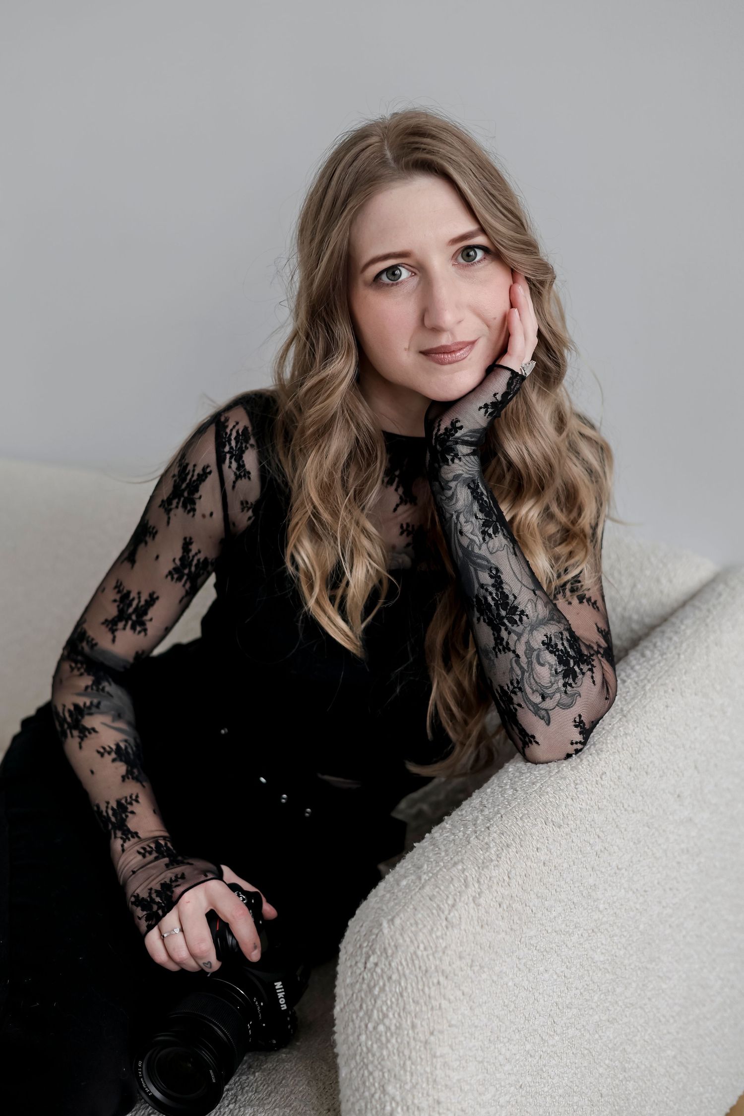 A series of portrait photos showing someone in a black lace top posing against a light background.