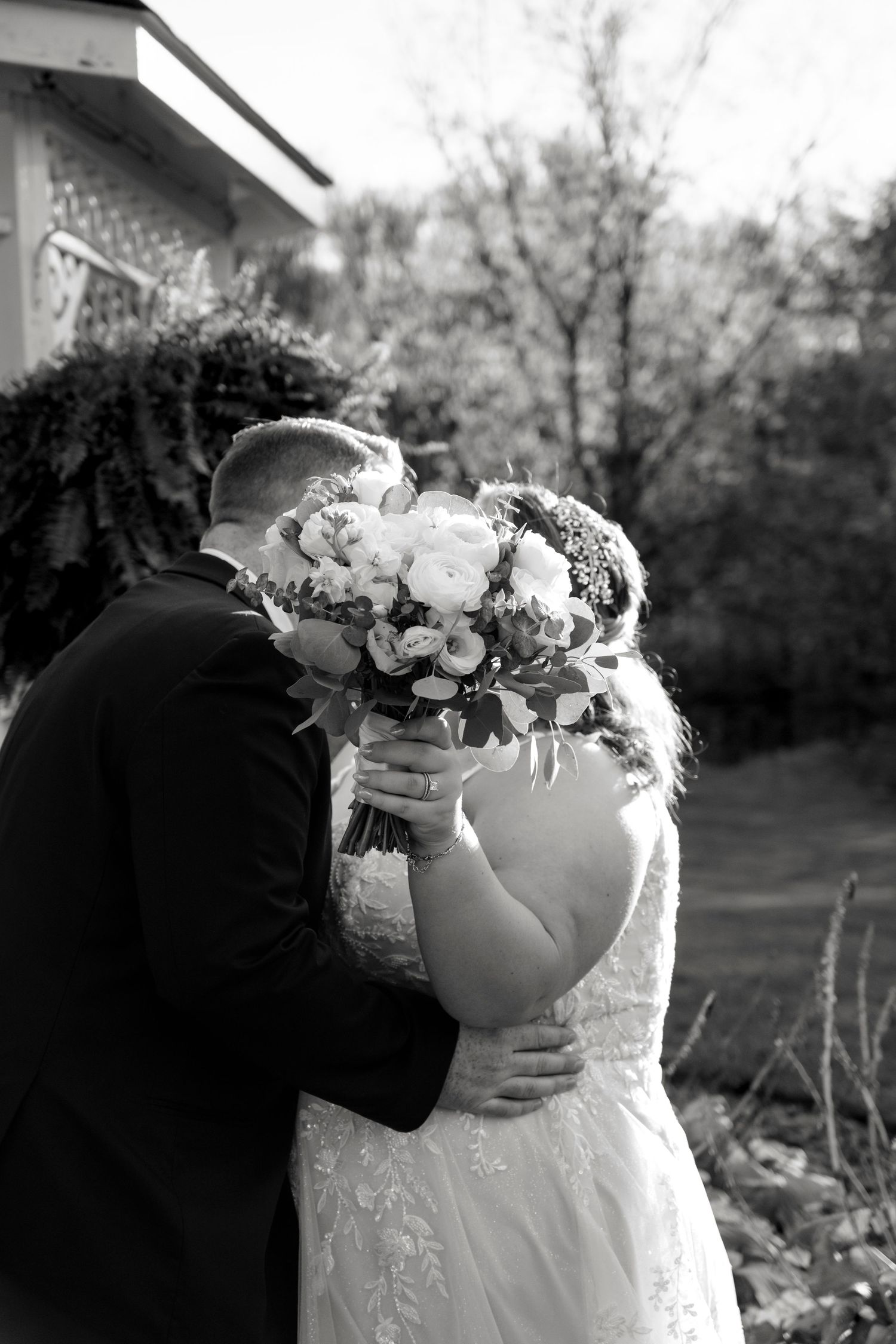 A romantic black and white wedding photo sequence showing a couple embracing and sharing an intimate moment outdoors.