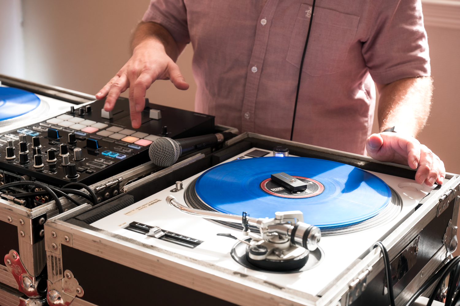 DJ mixing music on turntables with blue vinyl record and mixer equipment at an indoor event.