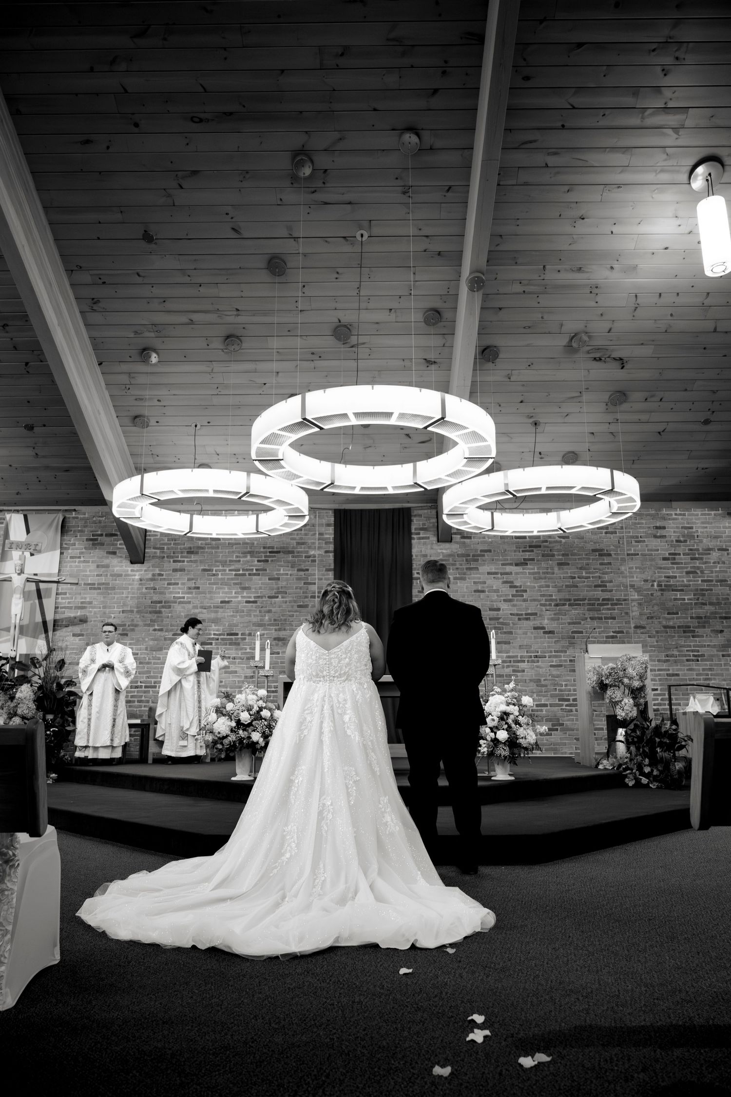 A wedding dress display in a dimly lit room with circular overhead lights and brick walls creating an elegant ambiance.