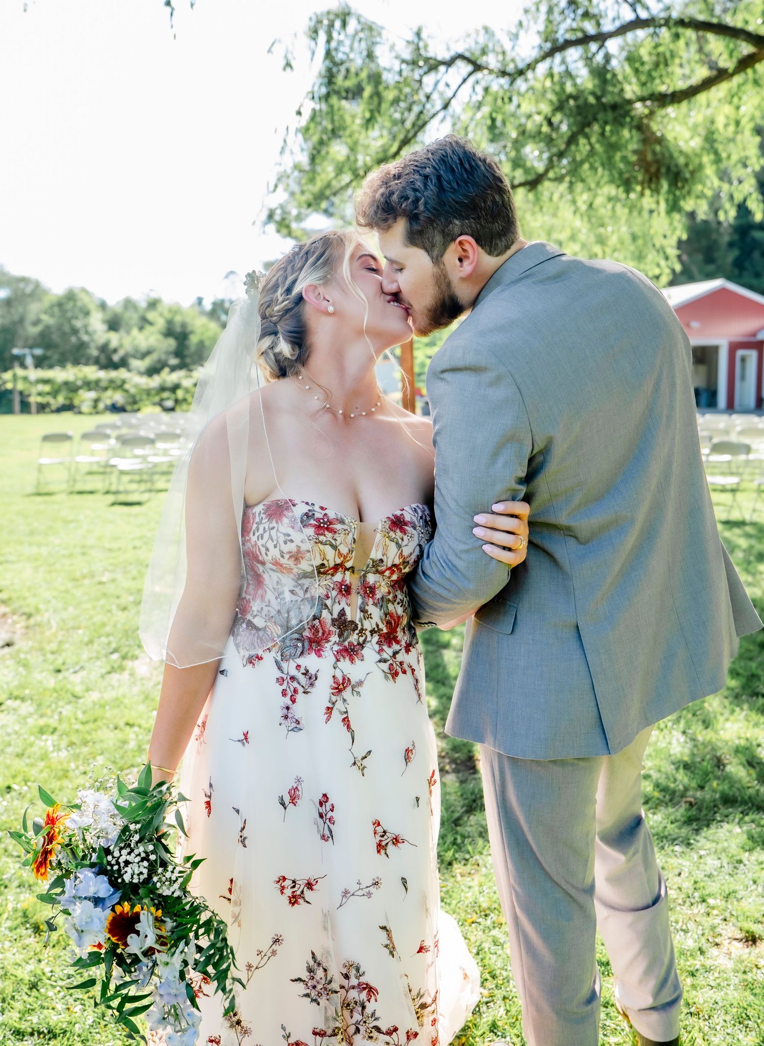 A romantic outdoor wedding photoshoot featuring a floral dress and gray suit in a garden setting.