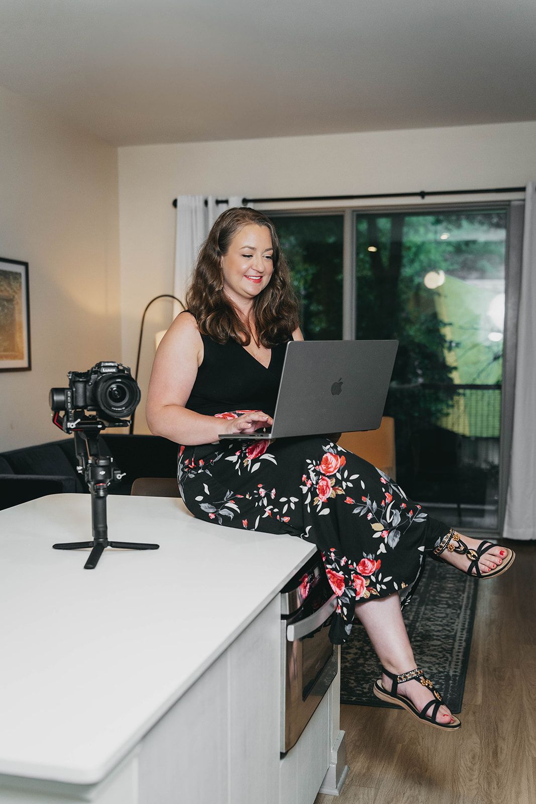 Professional photographer working on laptop while sitting at white desk.