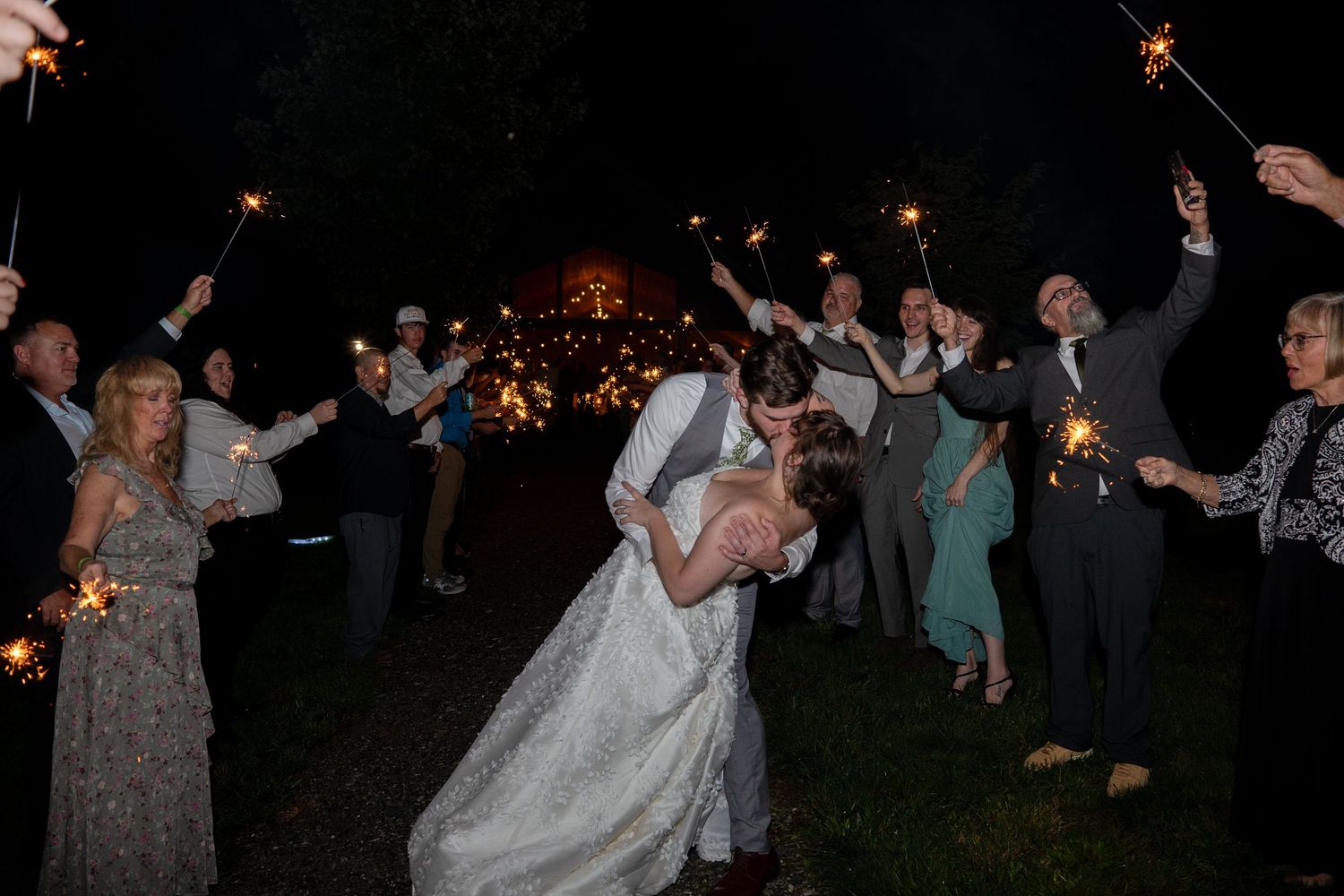 Evening wedding party with guests dancing and celebrating under string lights.