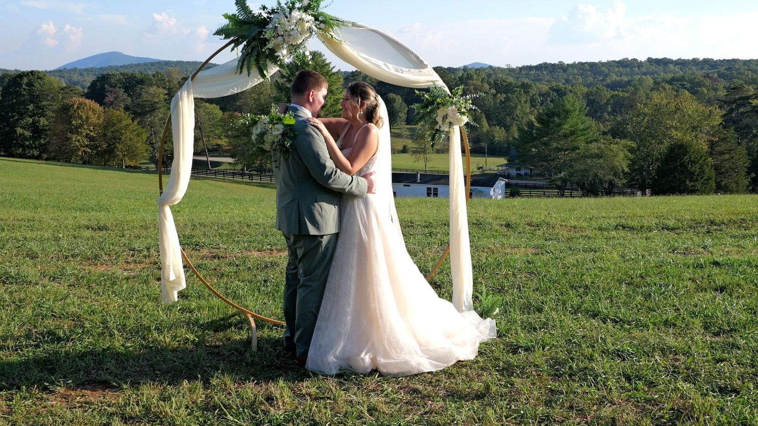 Wedding couple shares romantic moments in a scenic outdoor setting with rolling hills and greenery.