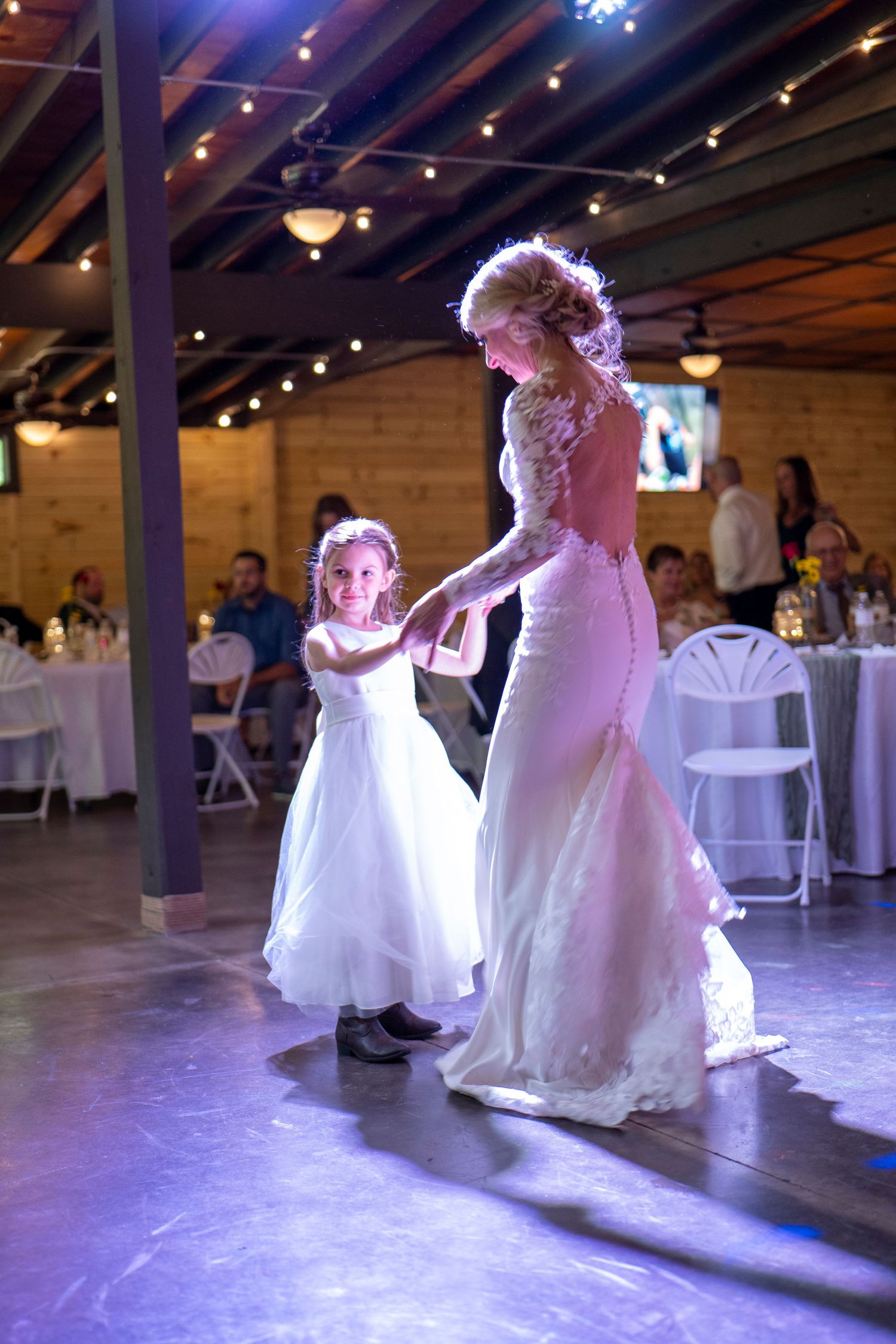 Wedding reception dance floor with purple lighting and string lights overhead.