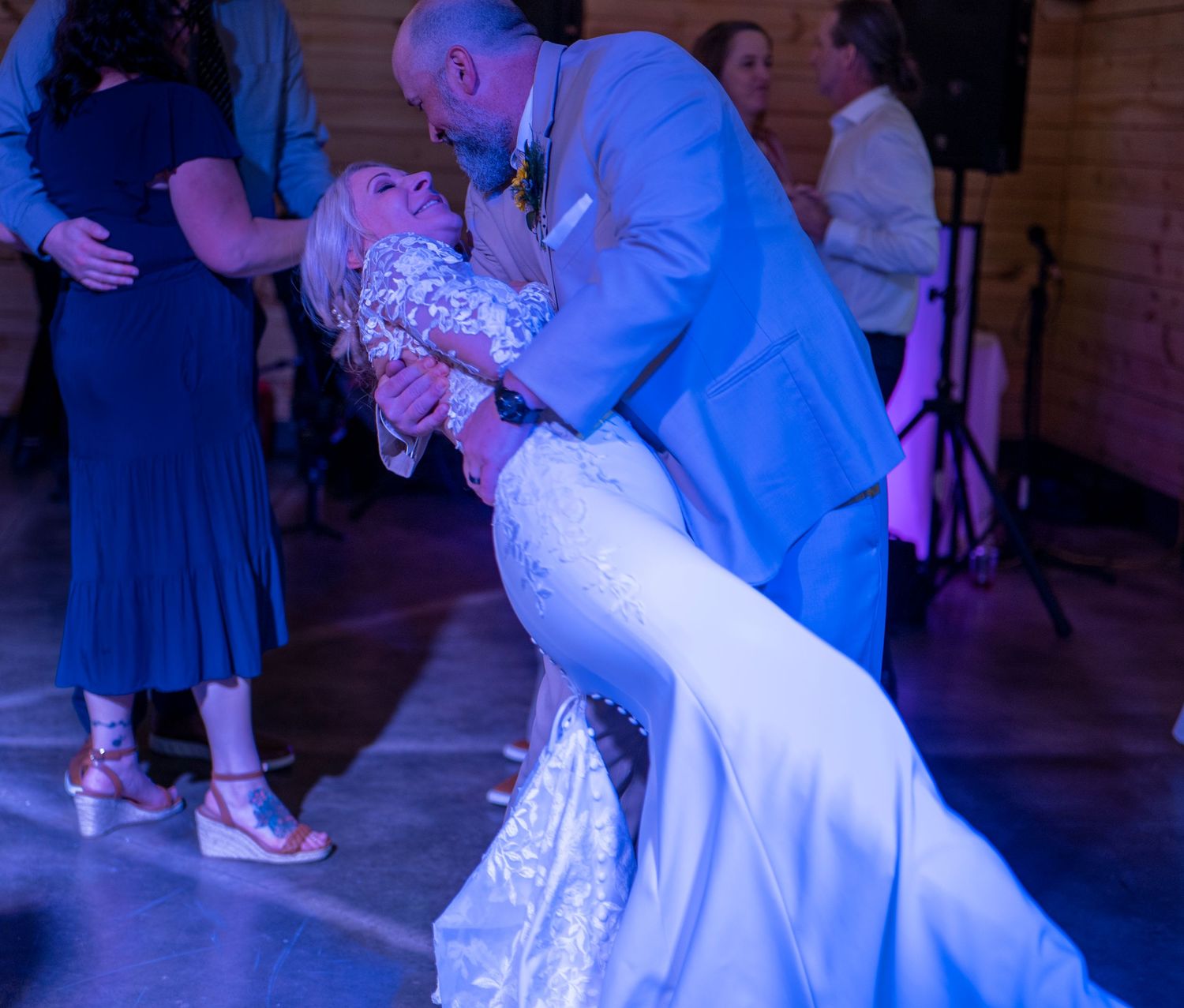 Wedding dance floor moments captured in dramatic blue lighting.