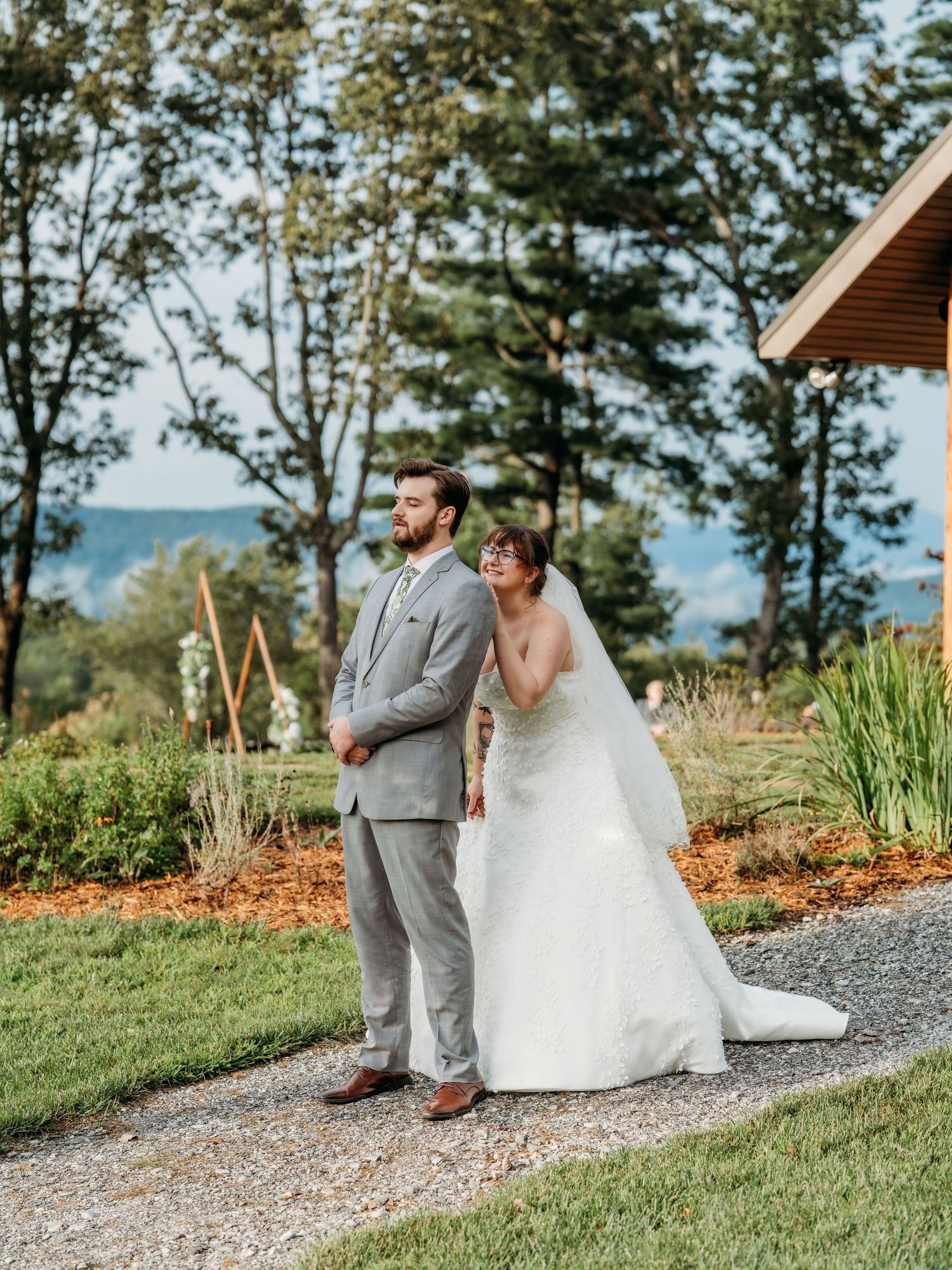 Bride and groom sitting on stone path surrounded by lush garden landscape.