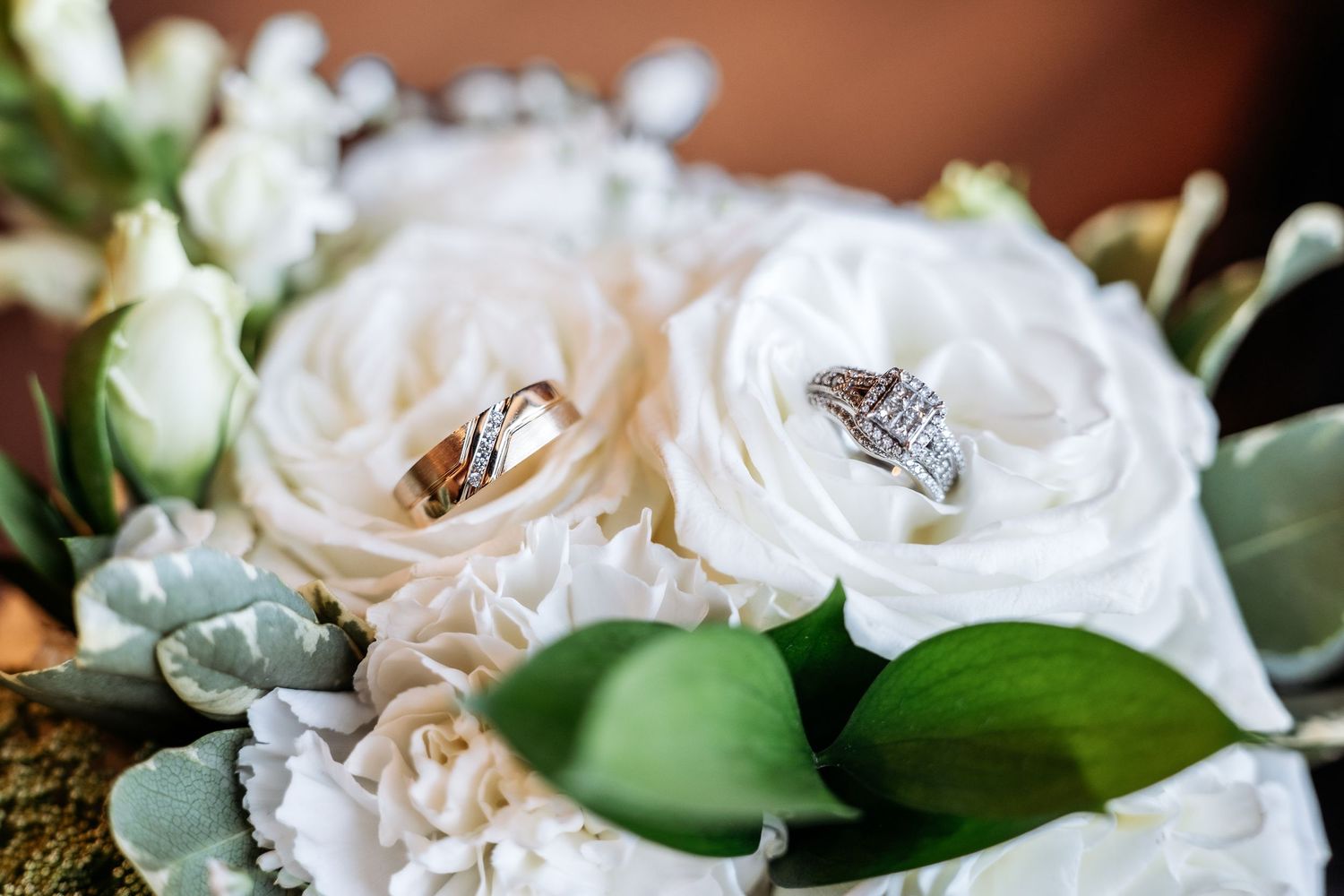 Close-up of delicate white and cream roses with green foliage.